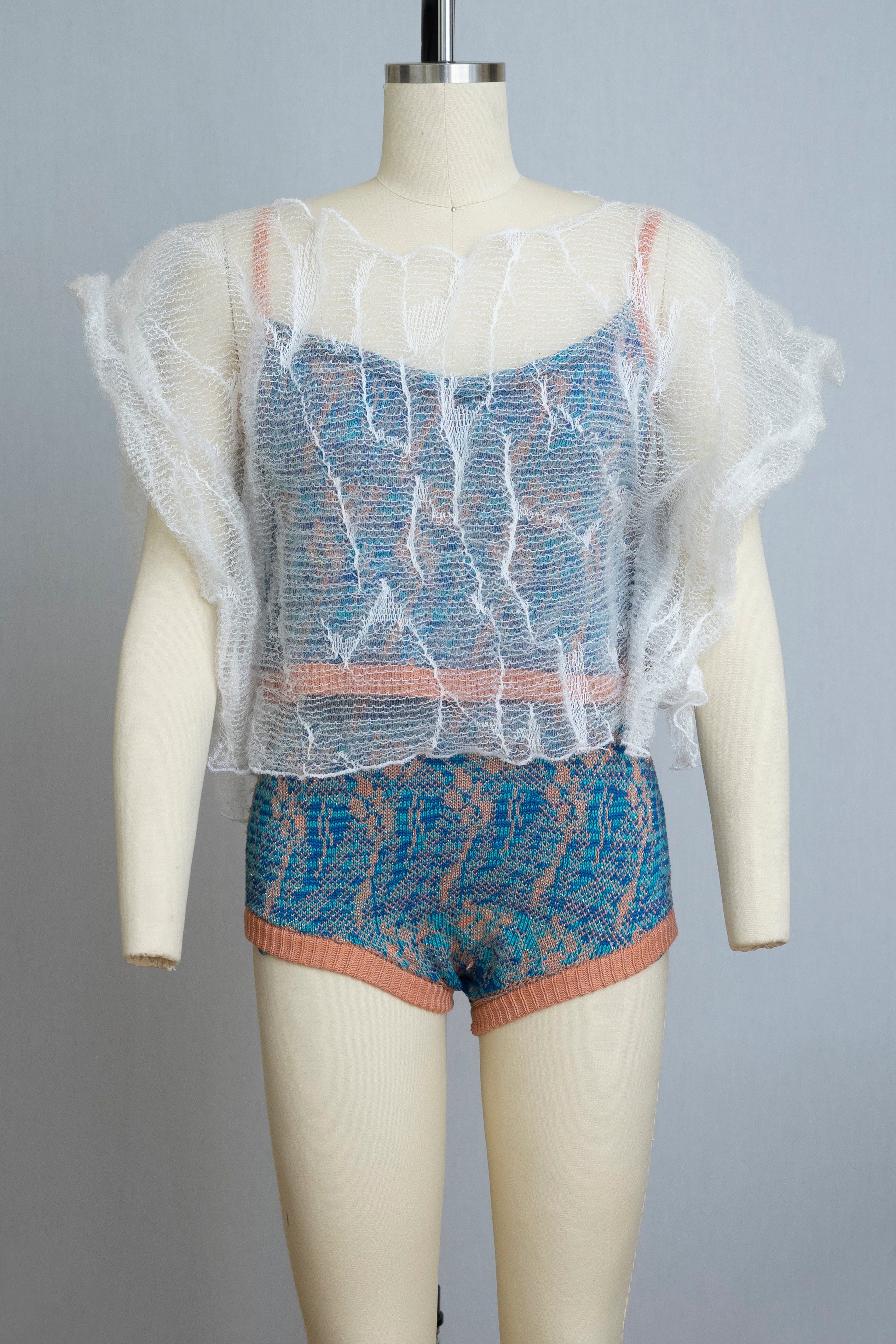 dress form wearing a knit playsuit in blues and pink with a sheer knit top