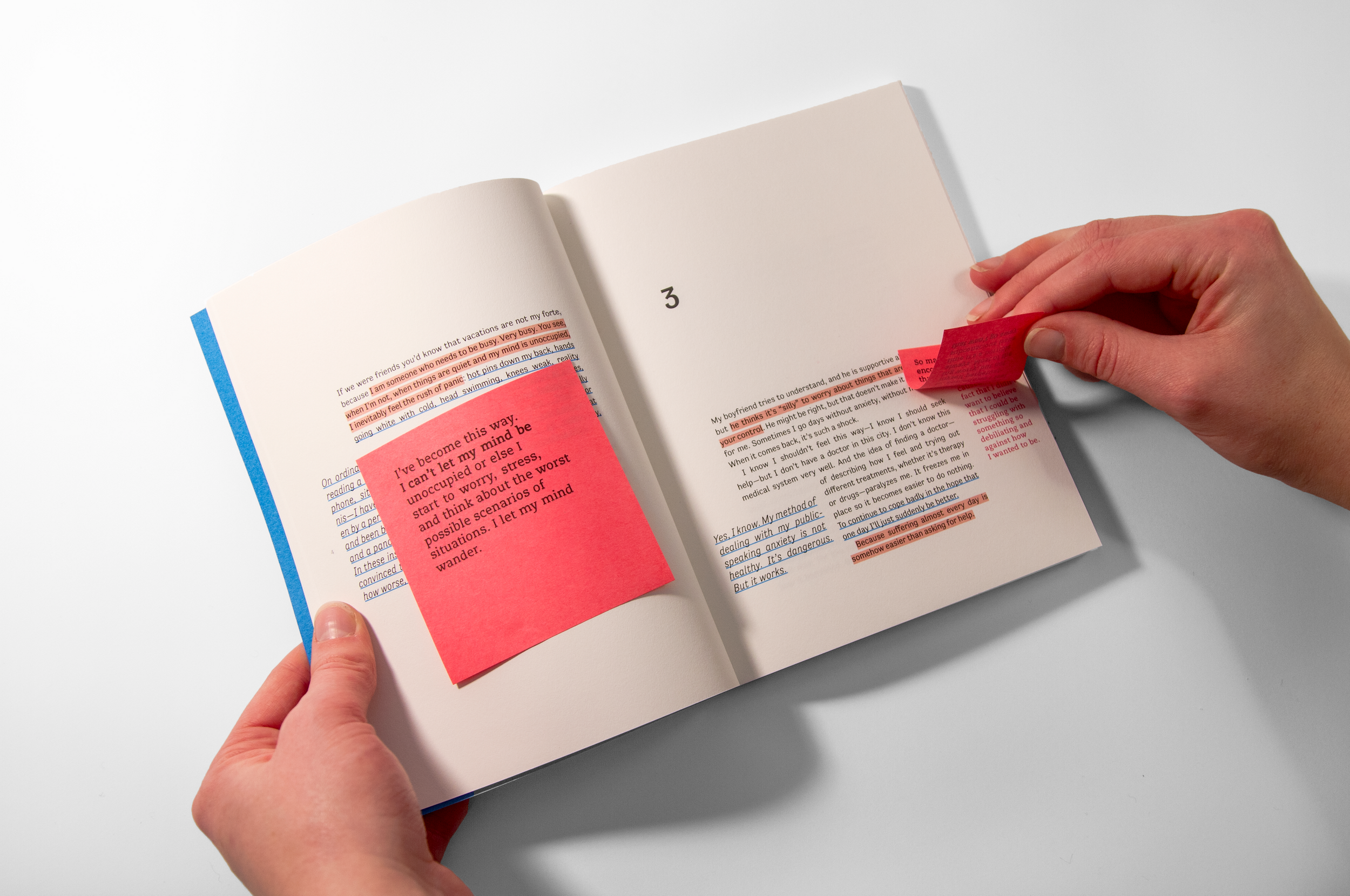 Hands holding an open book spread with post-it notes and highlighted text