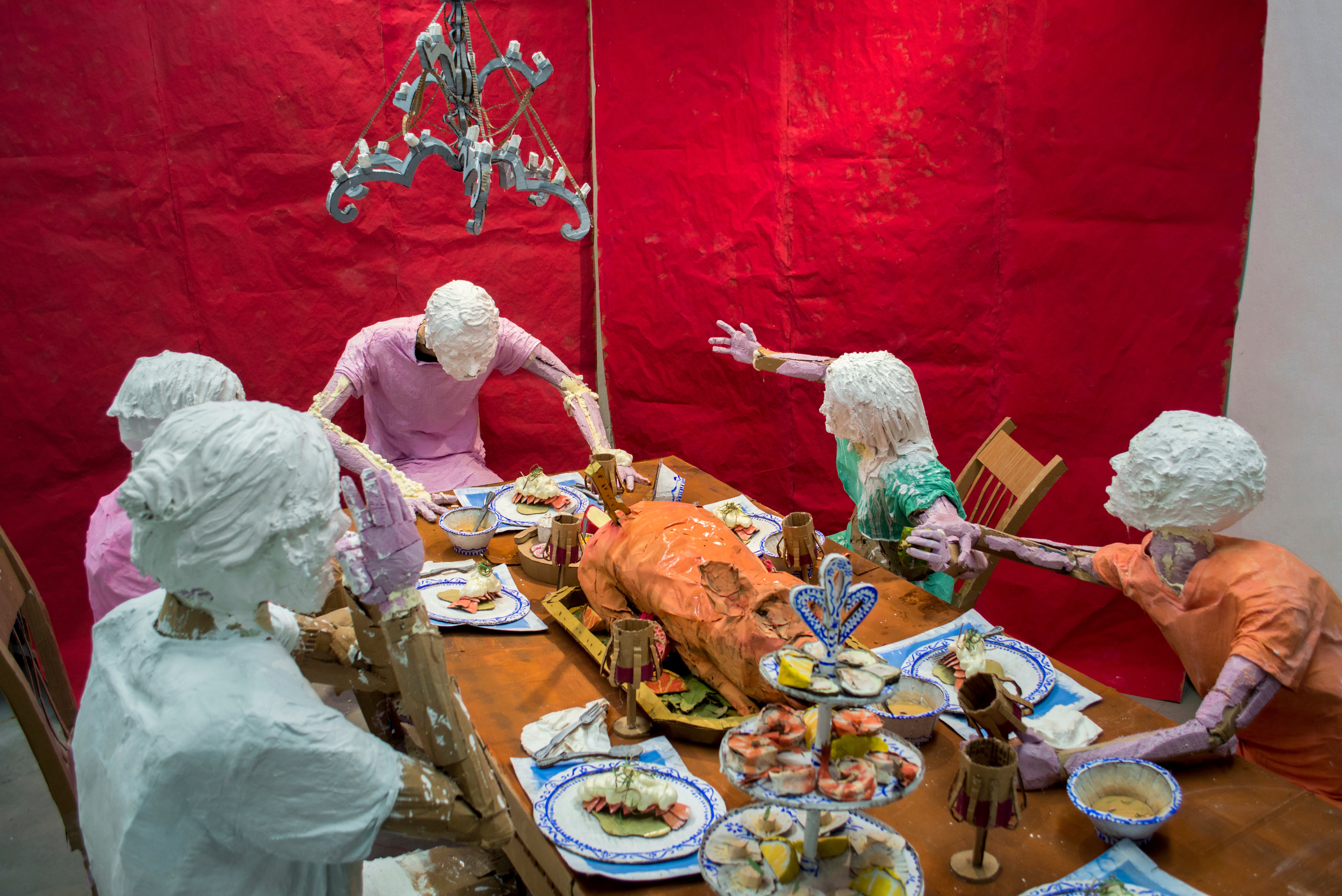 Installation sculpture of a group of people sitting around a dinner table.