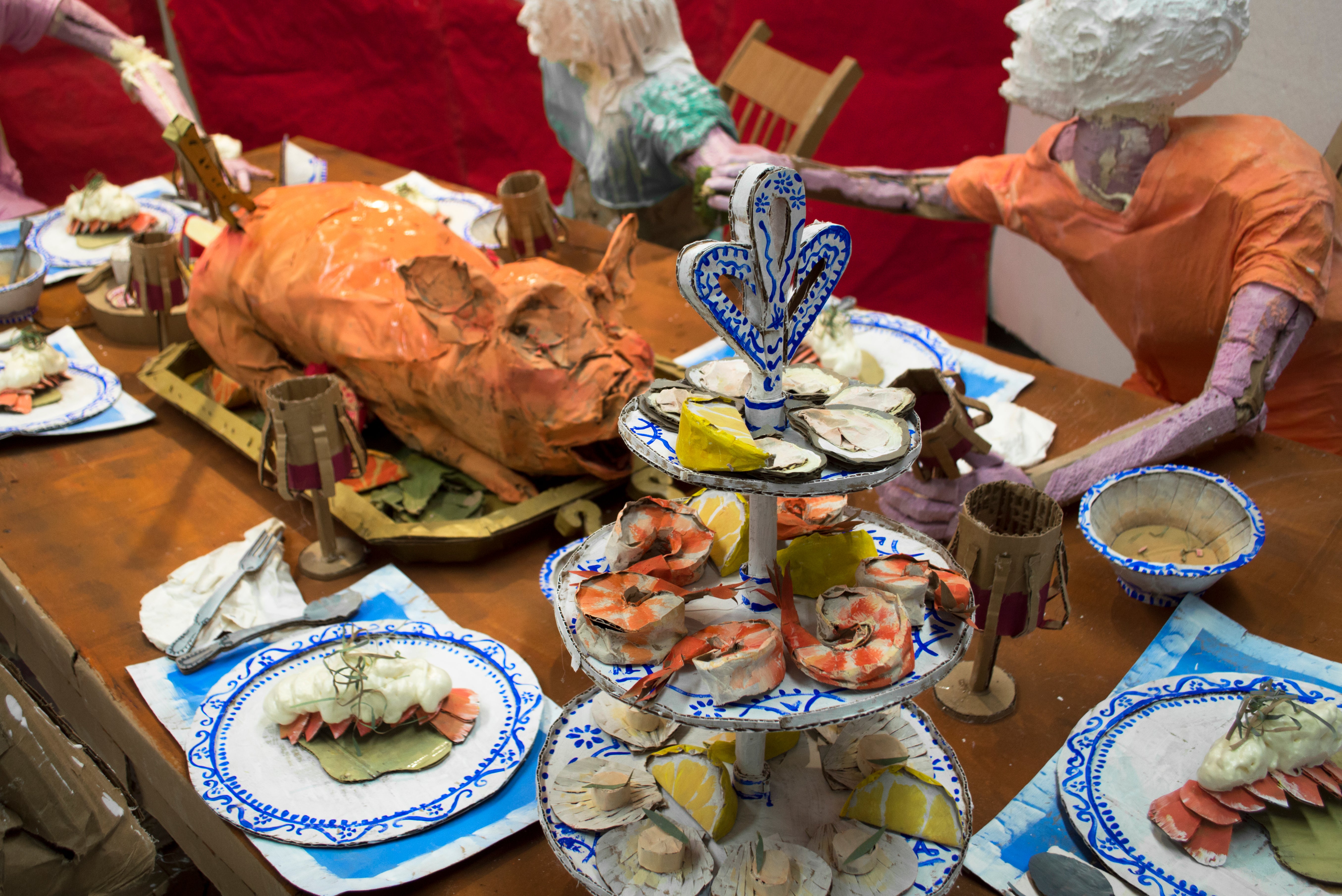Installation sculpture of a group of people sitting around a dinner table.