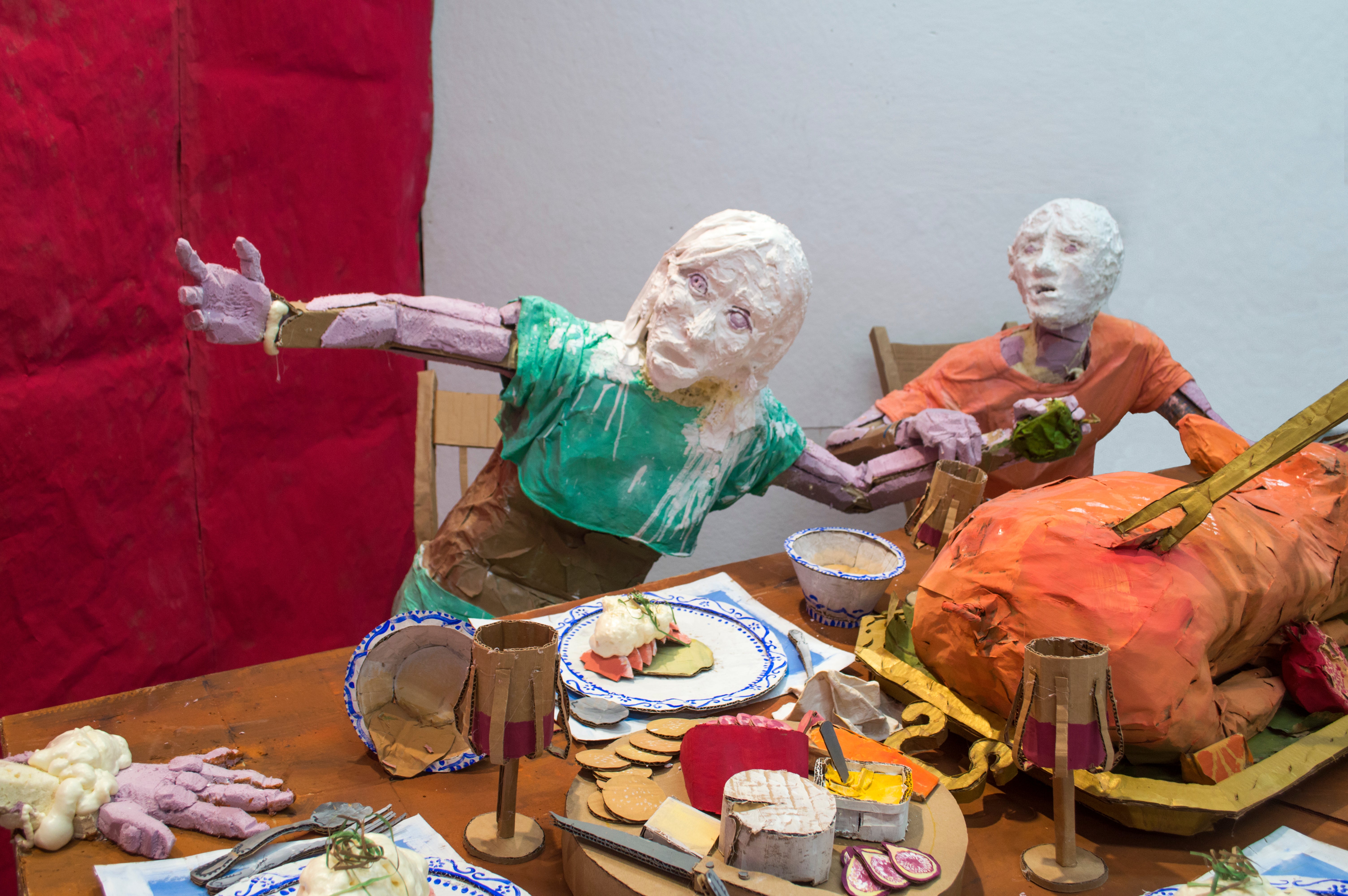 Installation sculpture of a group of people sitting around a dinner table.