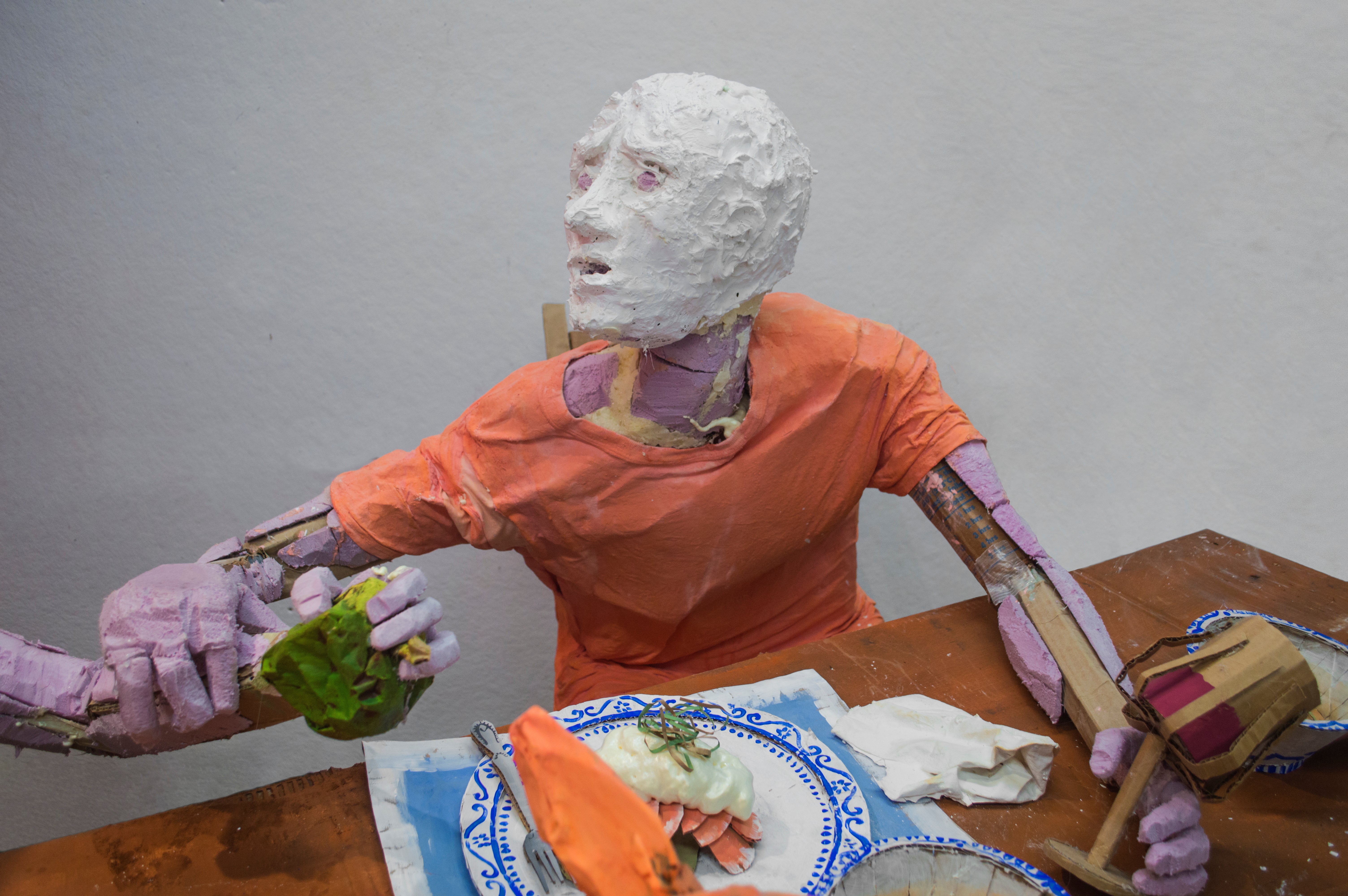 Installation sculpture of a group of people sitting around a dinner table.
