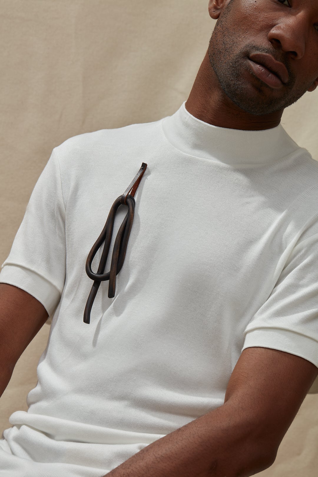 A dark knot brooch carved from wood, worn by a model