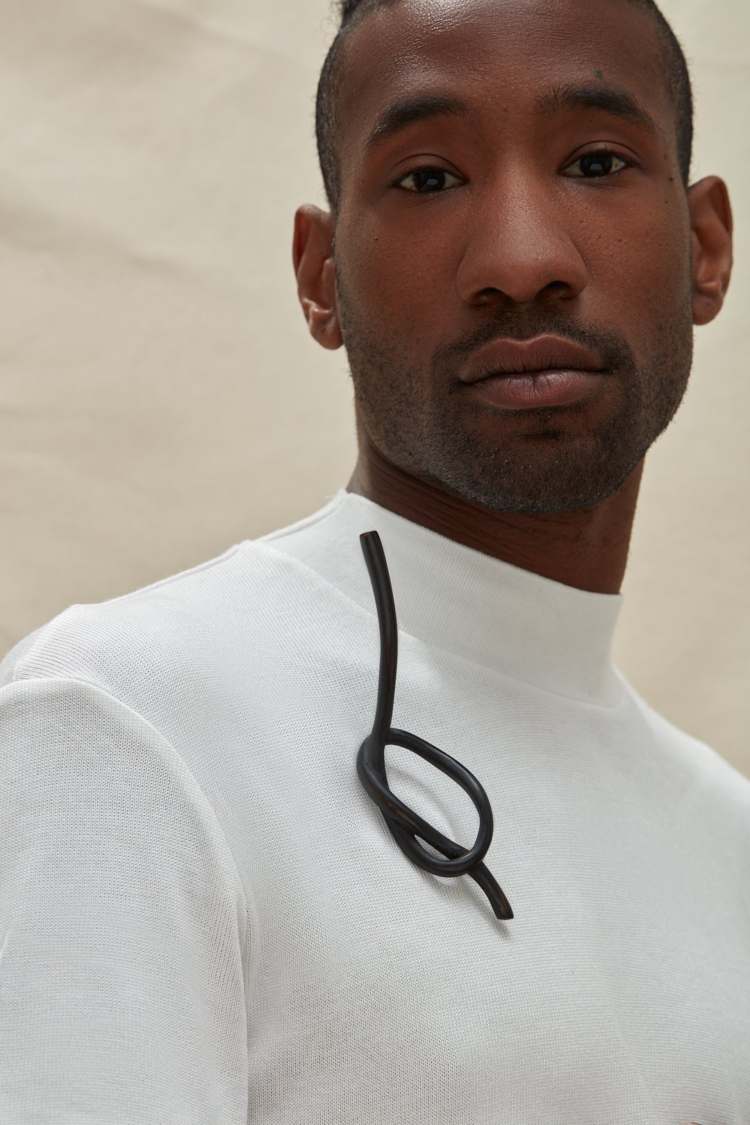 A dark knot brooch carved from wood, worn by a model