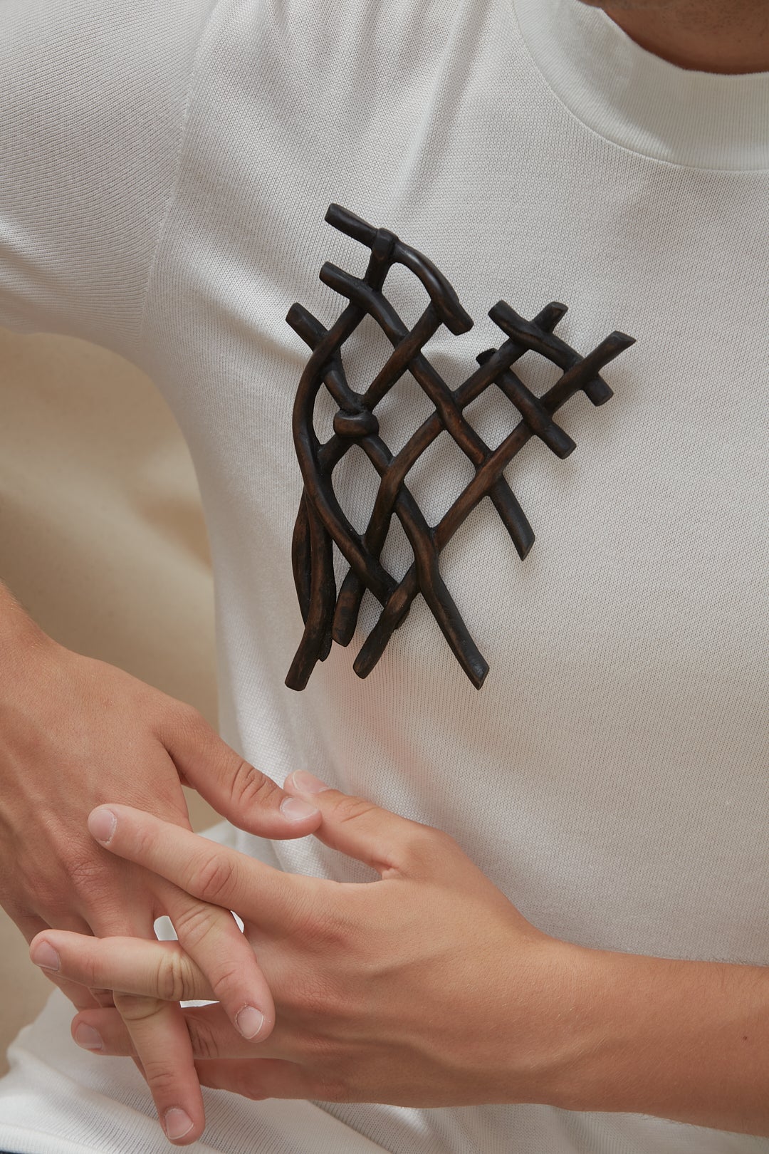 A dark knot brooch carved from wood, worn by a model