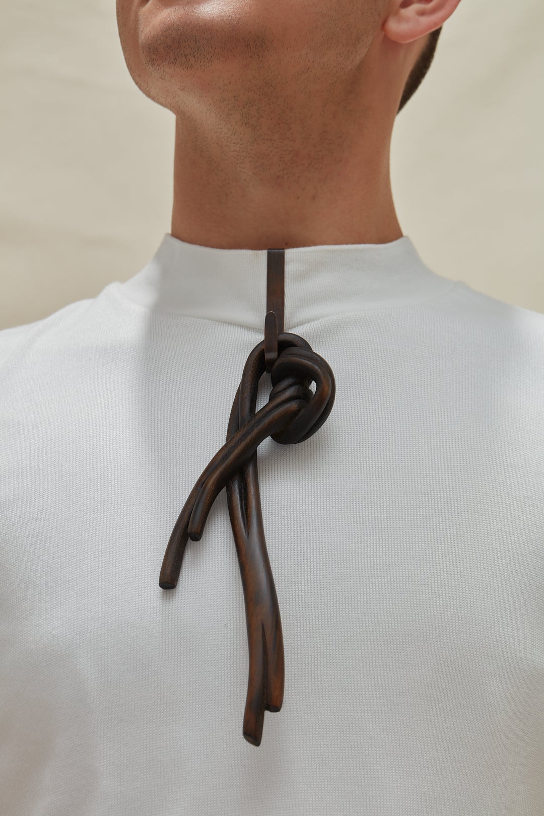 A dark knot brooch carved from wood, worn by a model