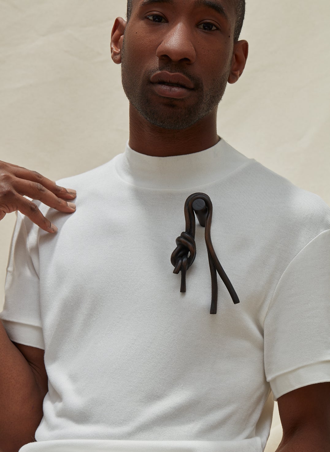 A dark knot brooch carved from wood, worn by a model