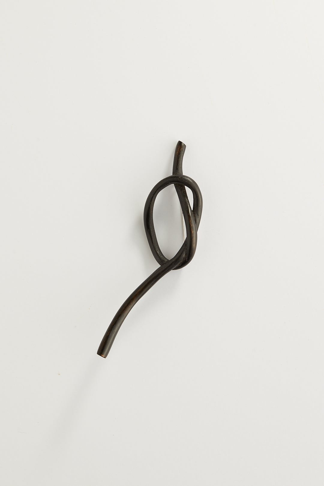 A dark knot brooch carved from wood