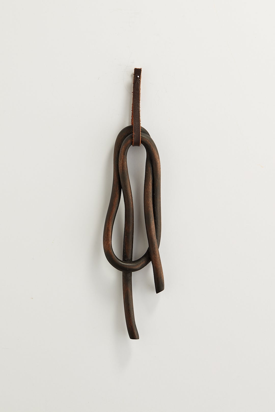 A dark knot brooch carved from wood