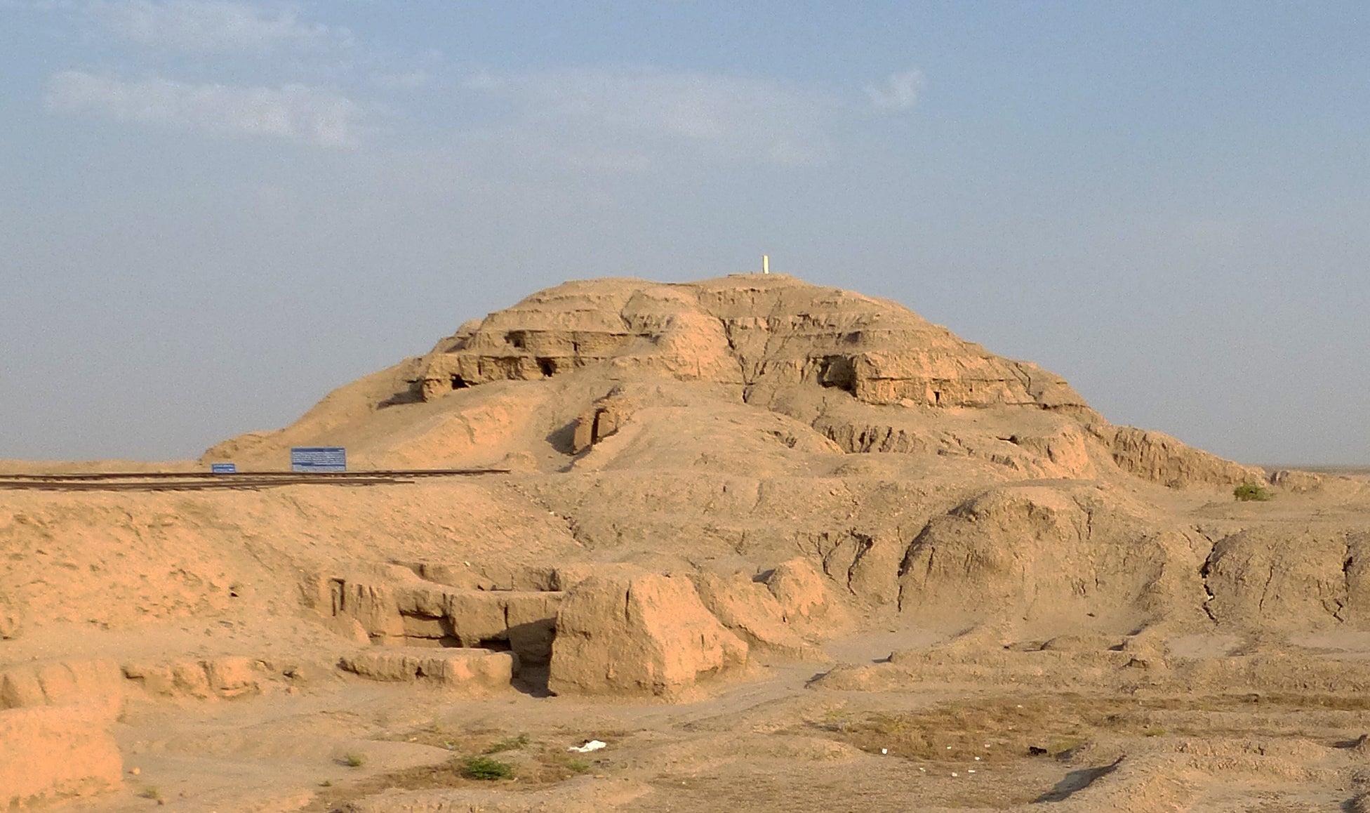 /color%20photograph%20of%20the%20Anu%20Ziggurat%20at%20Uruk.%20The%20remains%20of%20the%20stepped%20pyramid%20ziggurat%20emerge%20from%20the%20yellow%20sand%20desert%2C%20with%20blue%20sky%20above.