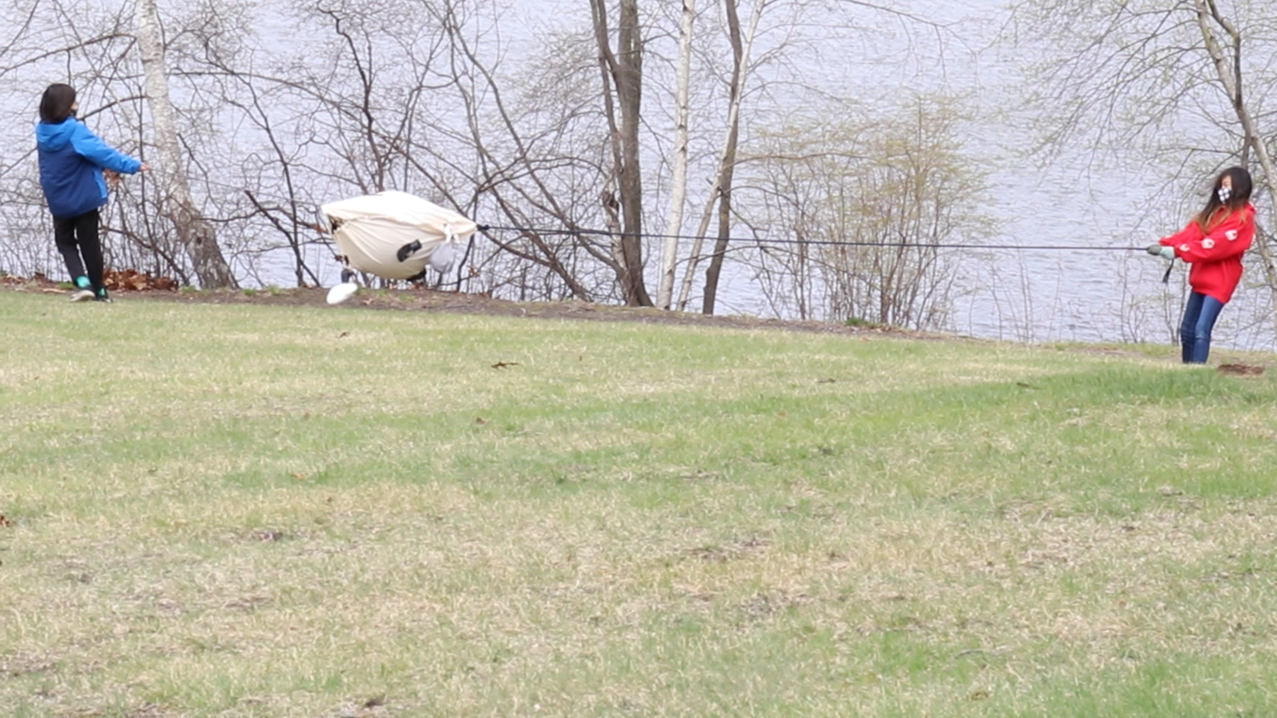 Two kids each pull on the ends of a rope, suspending a large toy between them.