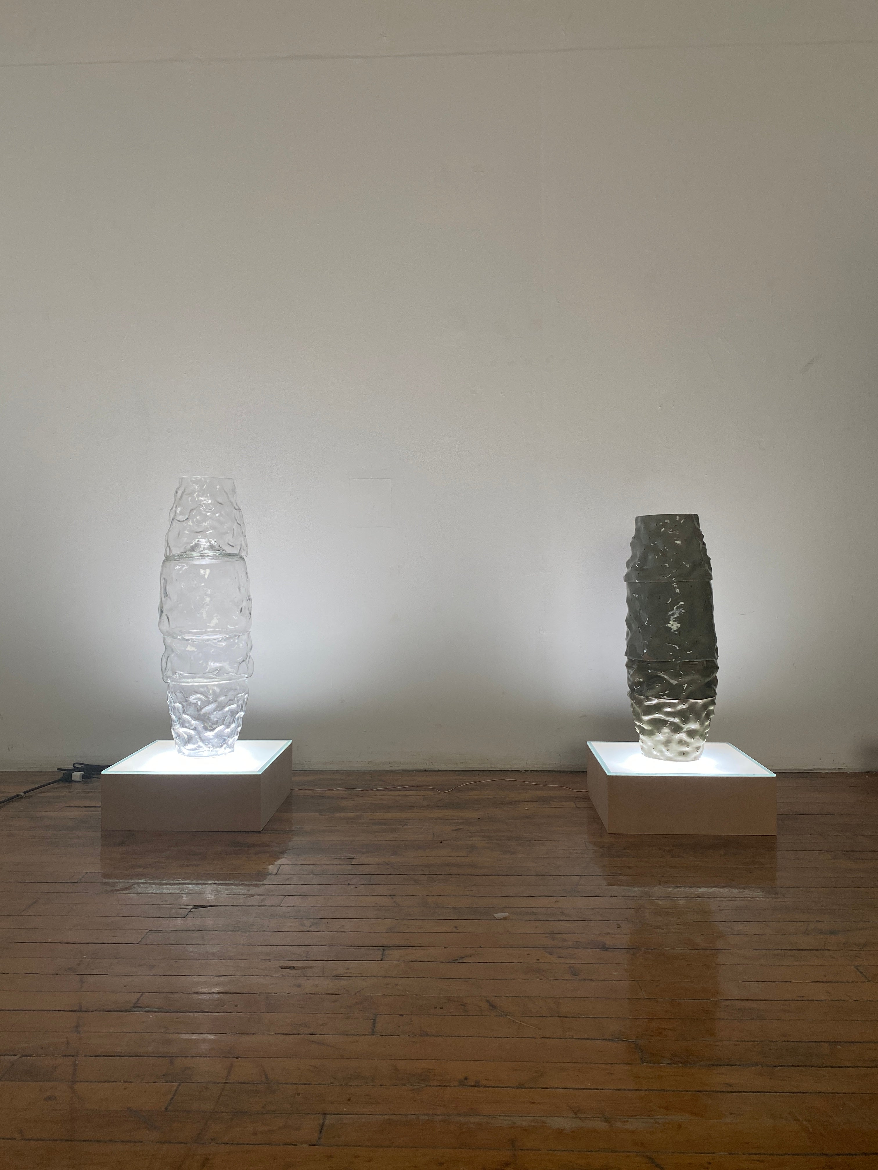 Corresponding towers of glass and ceramic atop glowing pedestals