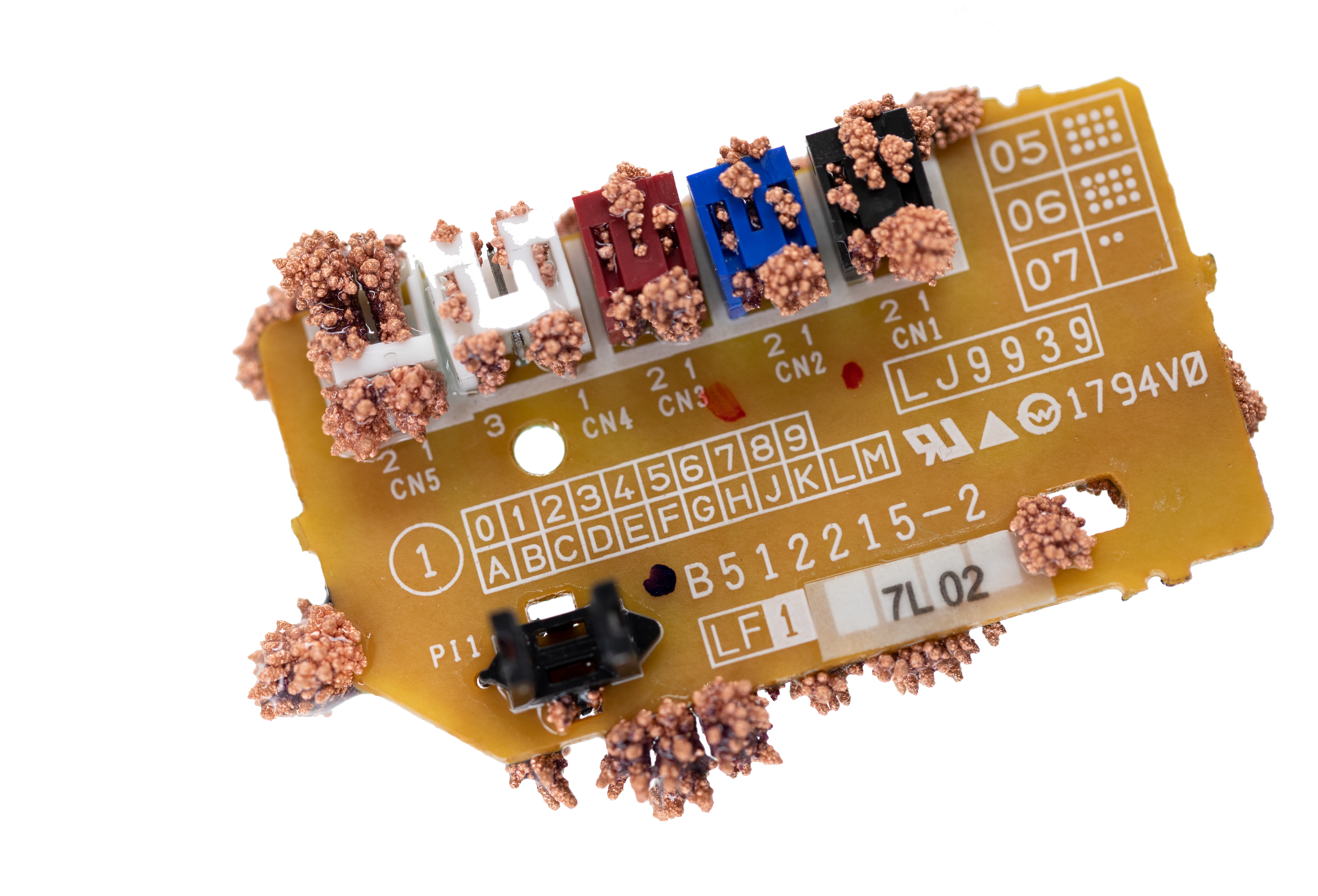 photograph of a small circuit board with copper crystals growing out of it