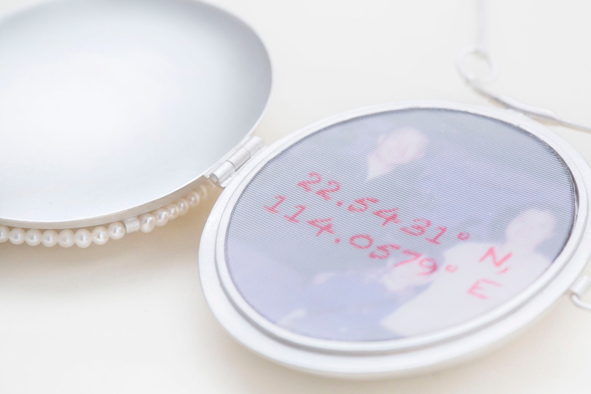 22.5431° N, 114.0579° E is a locket necklace, with lenticular print encased in the middle. 