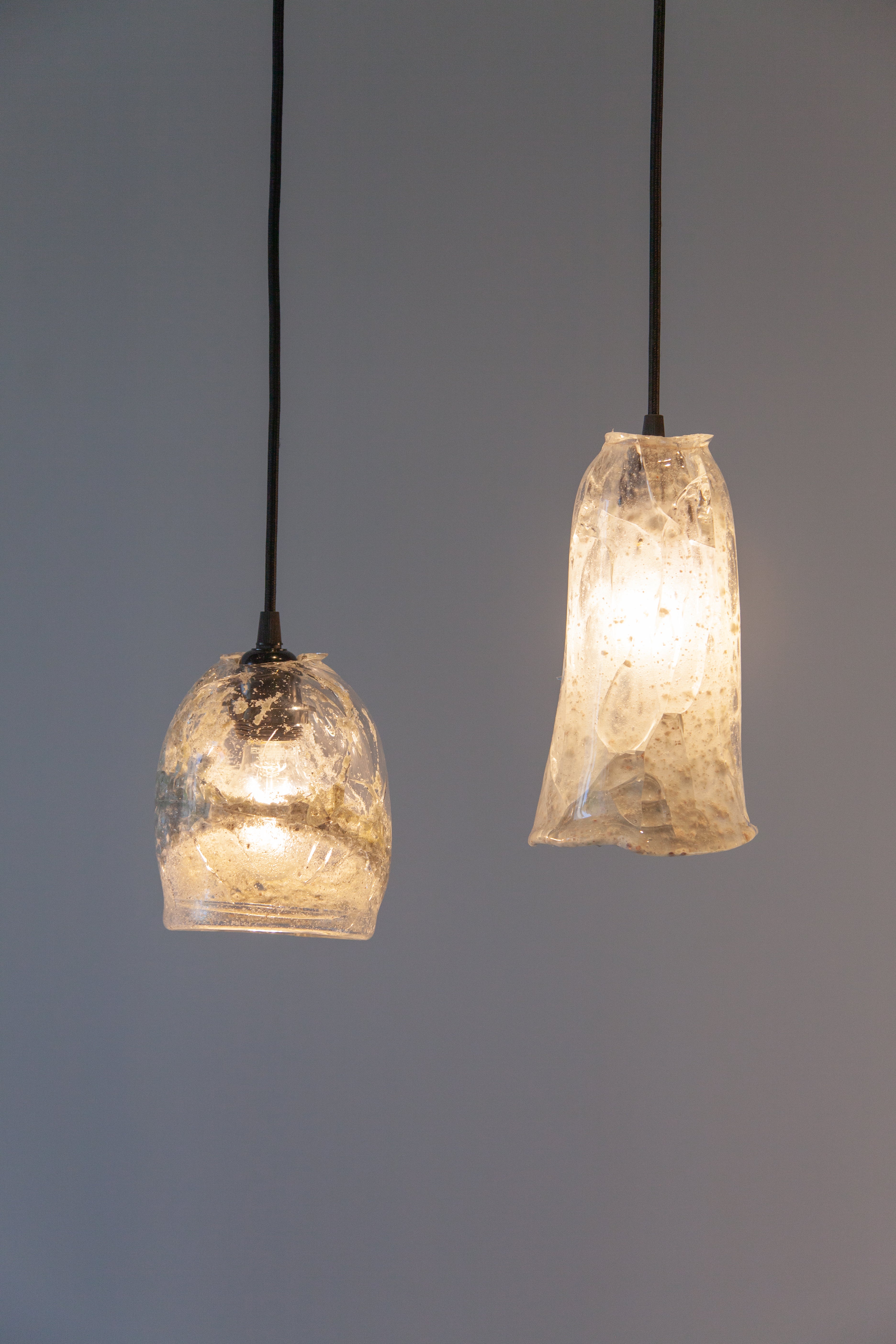 two hanging glass lamps made from glass of melted beach sand
