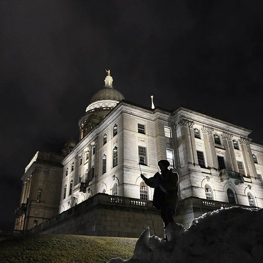 color photograph of the Providence capital building at night. It is lit from below, and the outline of a figure is visible in the foreground