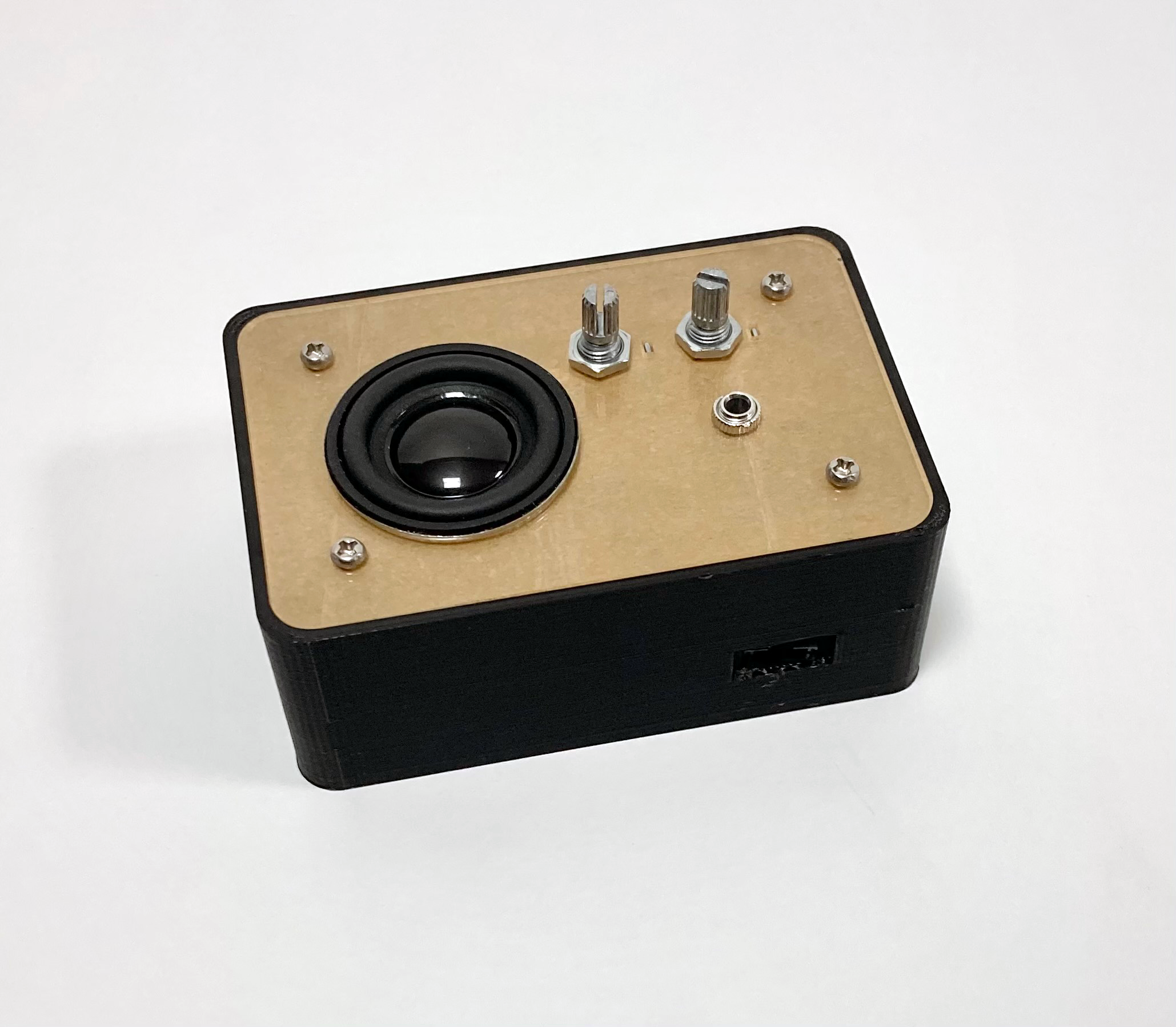 An instrument enclosed in a black plastic box, with a small speaker and two knobs visible on the top face.