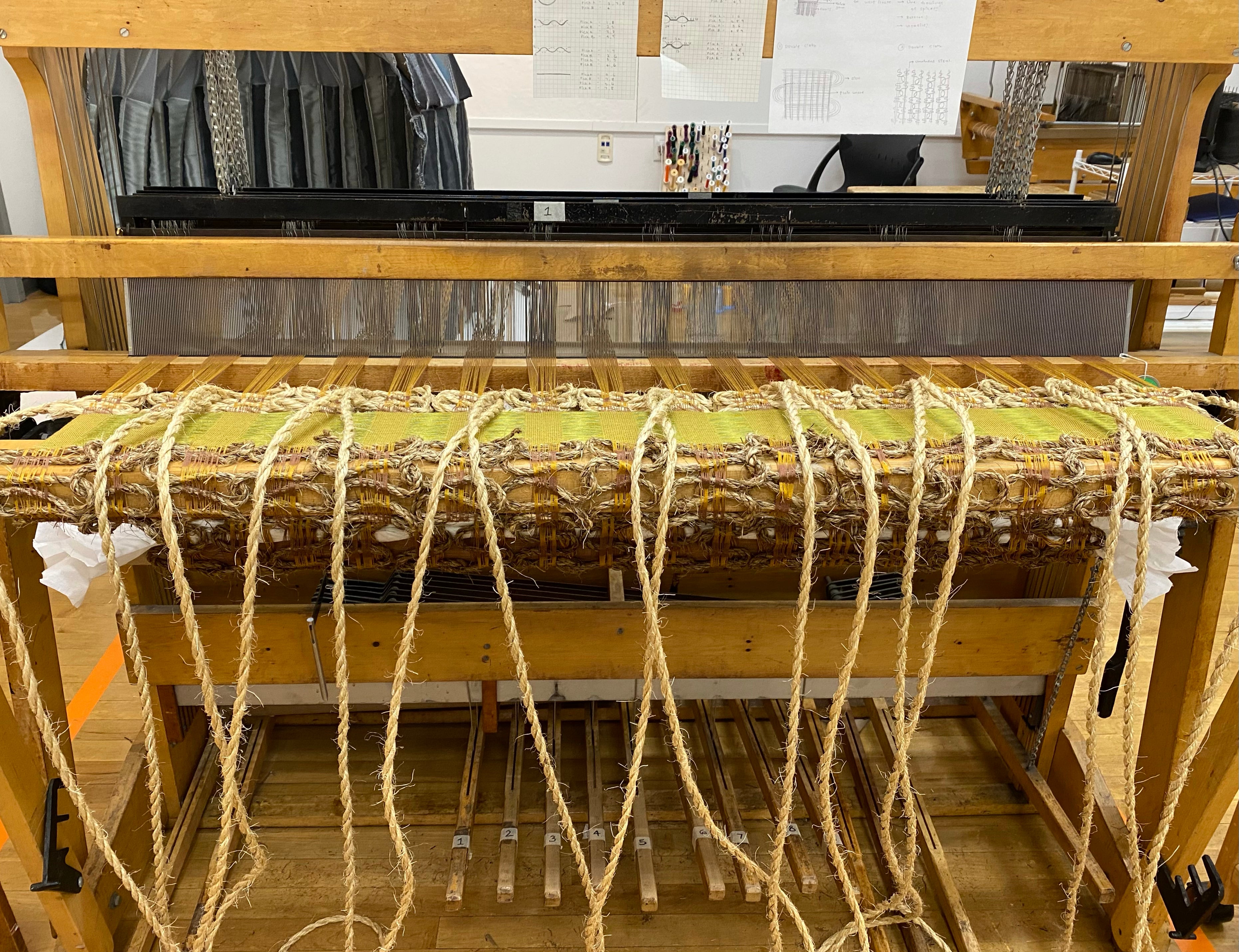 Image of the loom with handwoven piece on it