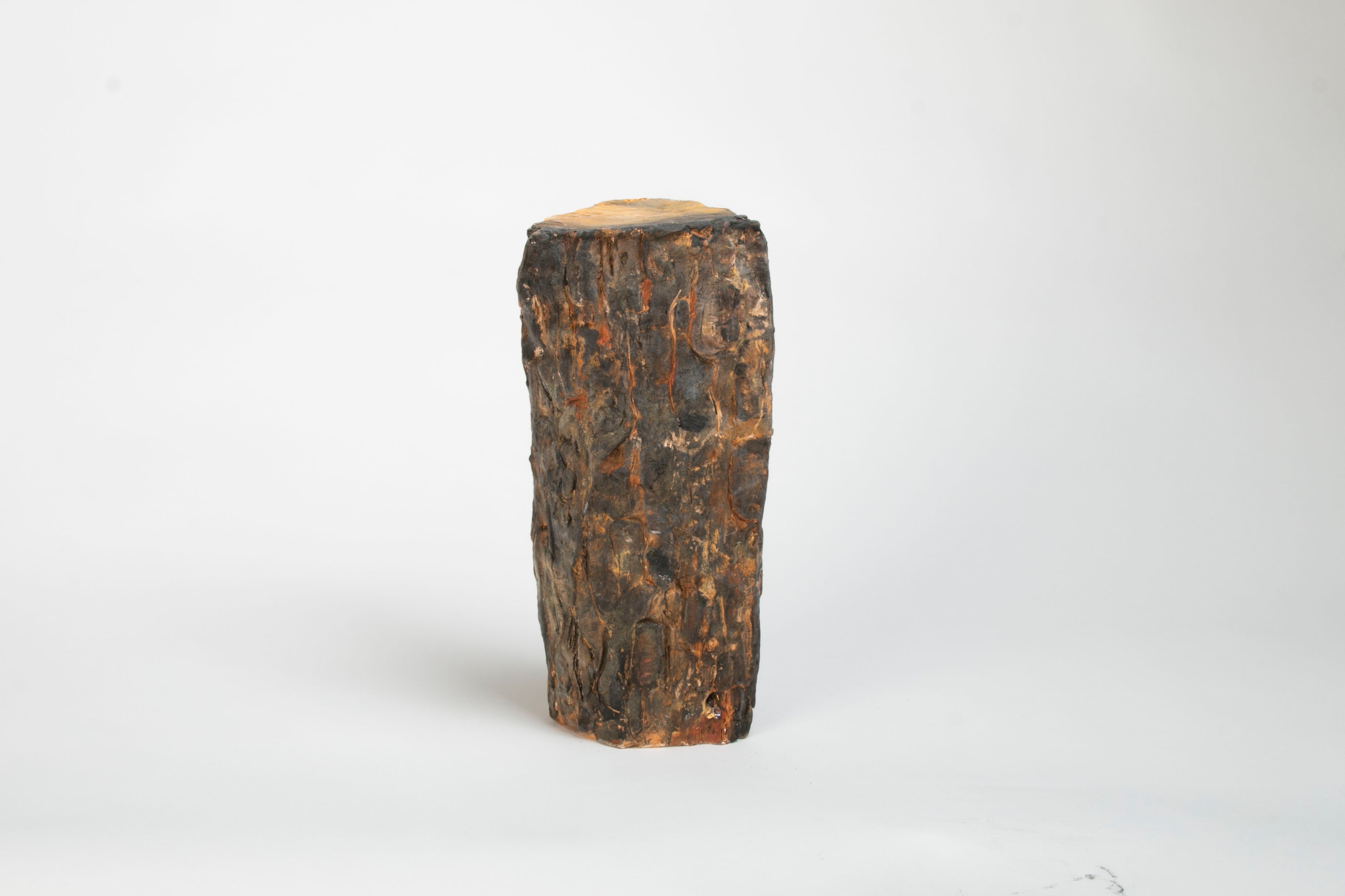 Ceramic sculpture resembling fire wood with shiny confetti spilling out of cracks and knots in wood.