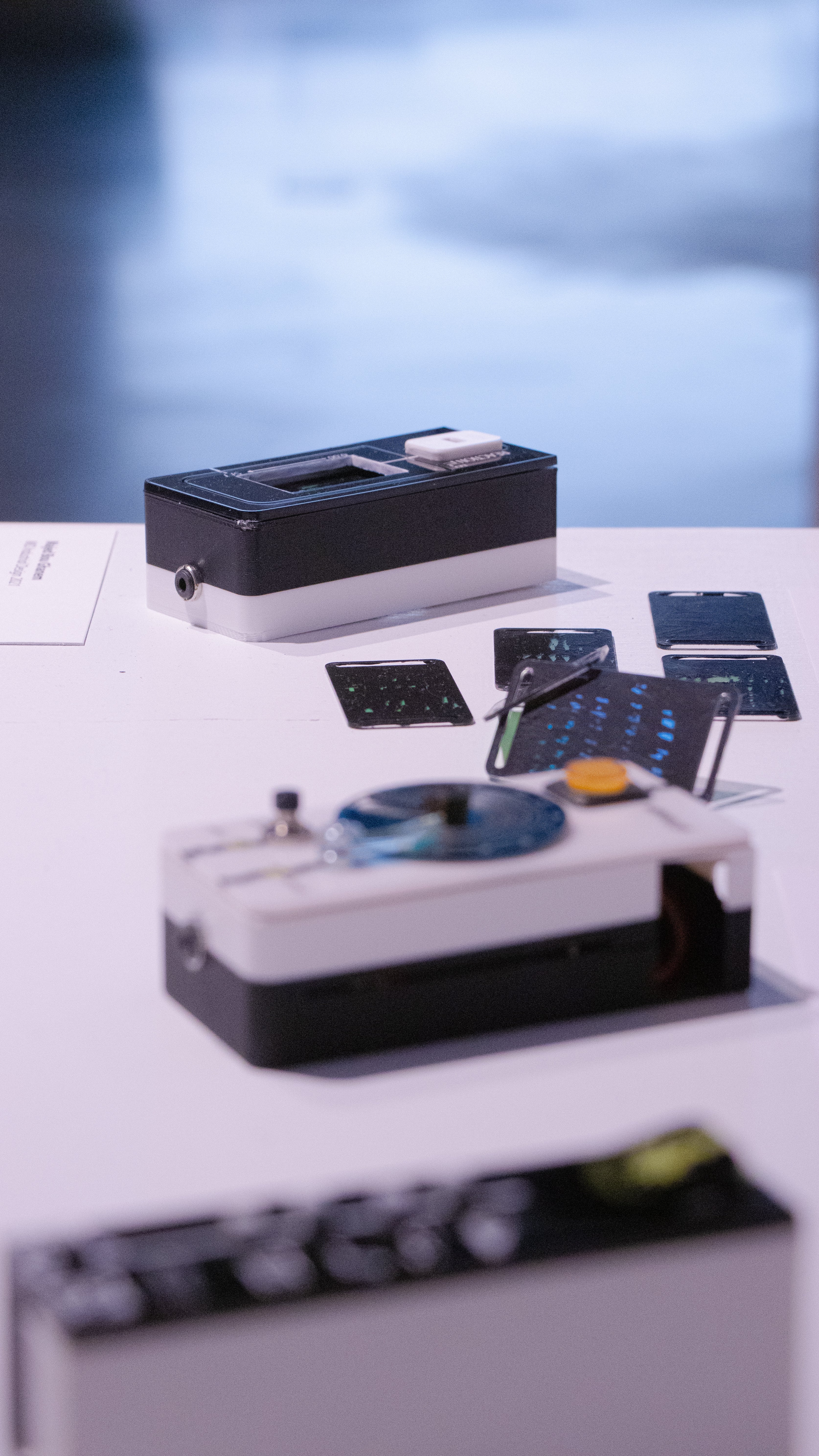 Portrait oriented photograph (vertical) showing the three devices. top to bottom: reaction tile, monofilter, vibelist. The reaction tile is in focus, the rest are blurry.