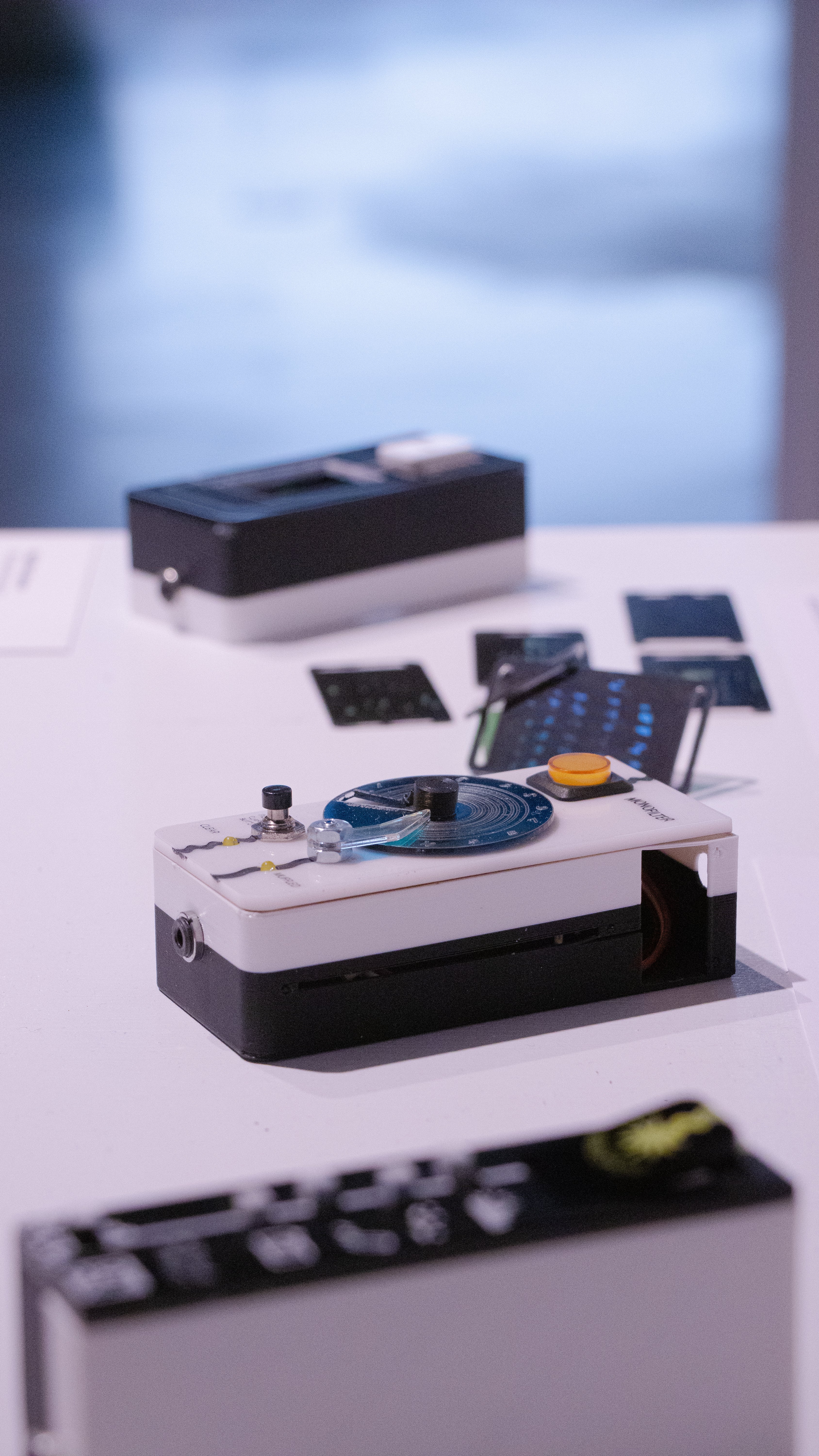 Portrait oriented photograph (vertical) showing the three devices. top to bottom: reaction tile, monofilter, vibelist. The monofilter is in focus, the rest are blurry.