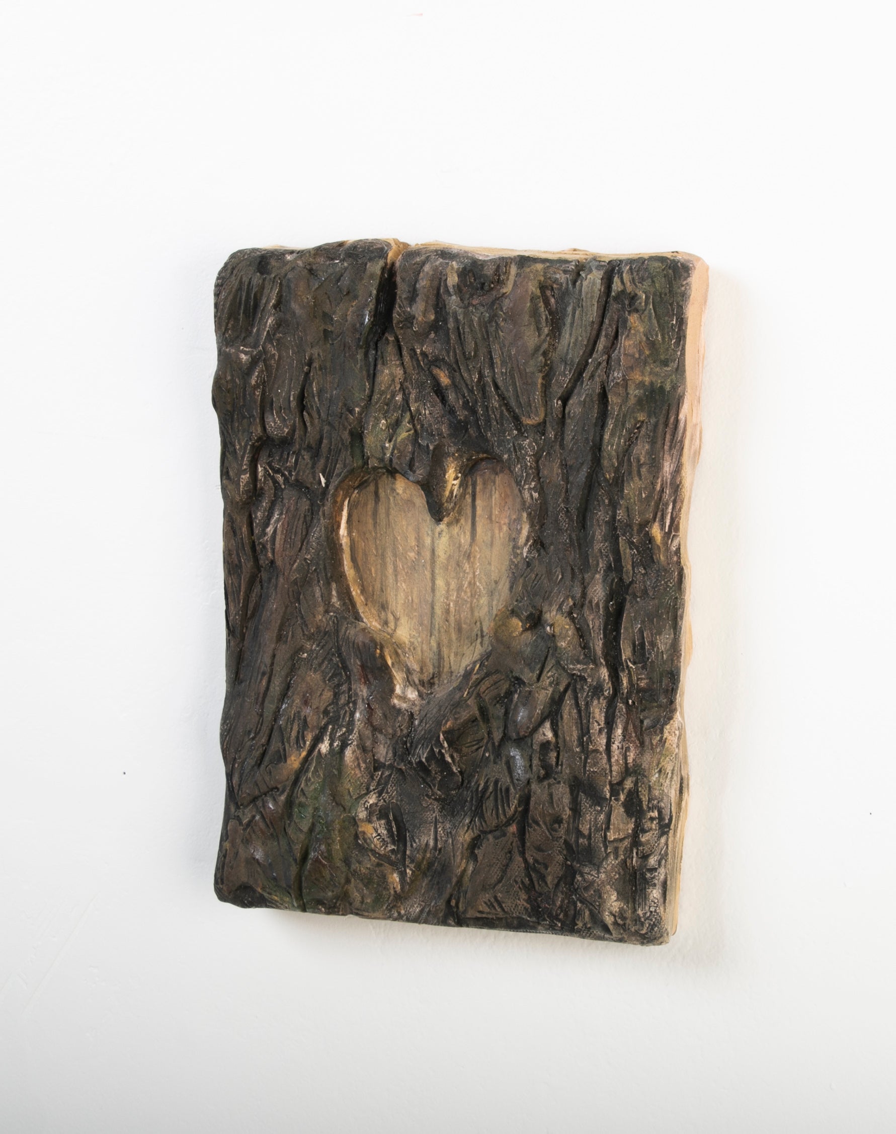 Clay sculpture of a heart cut out of tree
