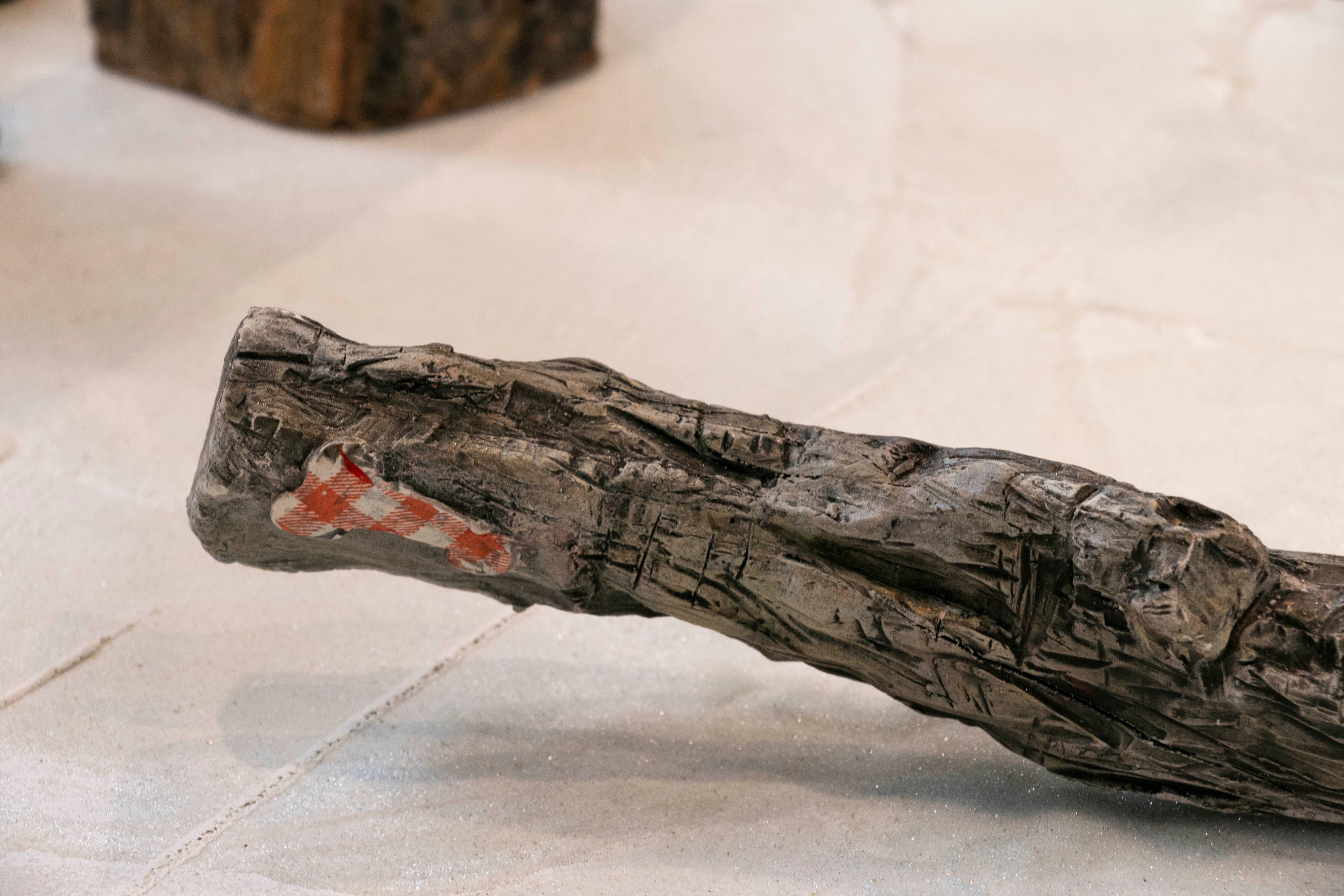 Detailed image of drift wood clay sculpture with patch of fabric shaped like a phallus.