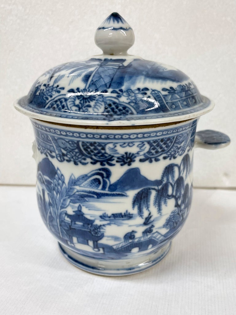 /A%20white%20ceramic%20sugar%20bowl%20with%20flat%20handles%20and%20lid%2C%20the%20decorations%20are%20architectural%20and%20floral.%20