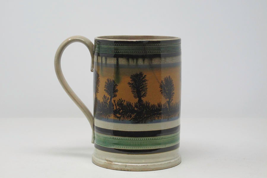 /An%20earthenware%20tankard%20that%20has%20white%2C%20blue%2C%20orange%2C%20green%2C%20and%20dark%20brown/black%20glaze%20vertical%20decorations.