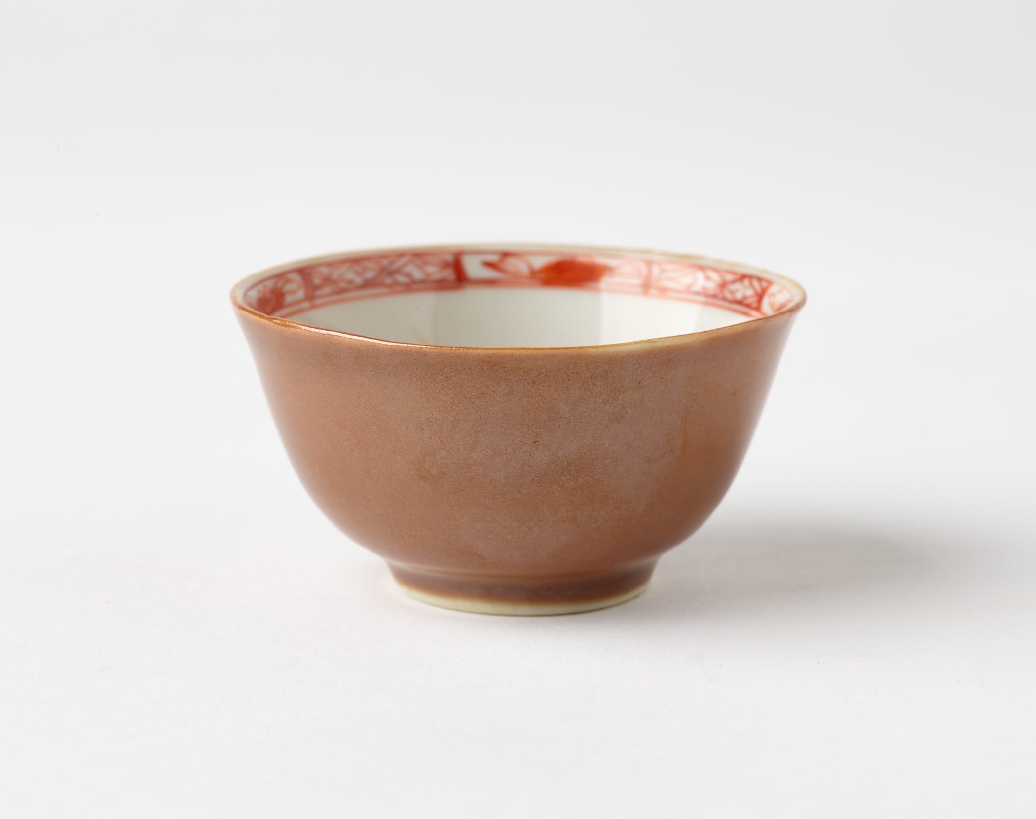 /A%20porcelain%20teacup%20with%20iron-red%20and%20gold%20floral%20and%20abstract%20decorations%20on%20the%20interior%20and%20an%20orange%20plain%20exterior.