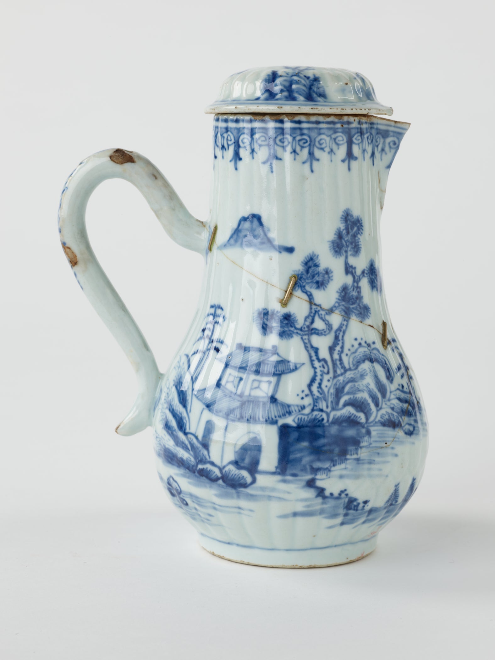 /A%20white%20chocolate%20pot%20with%20blue%20decorations%20depicting%20floral%20and%20architectural%20elements.