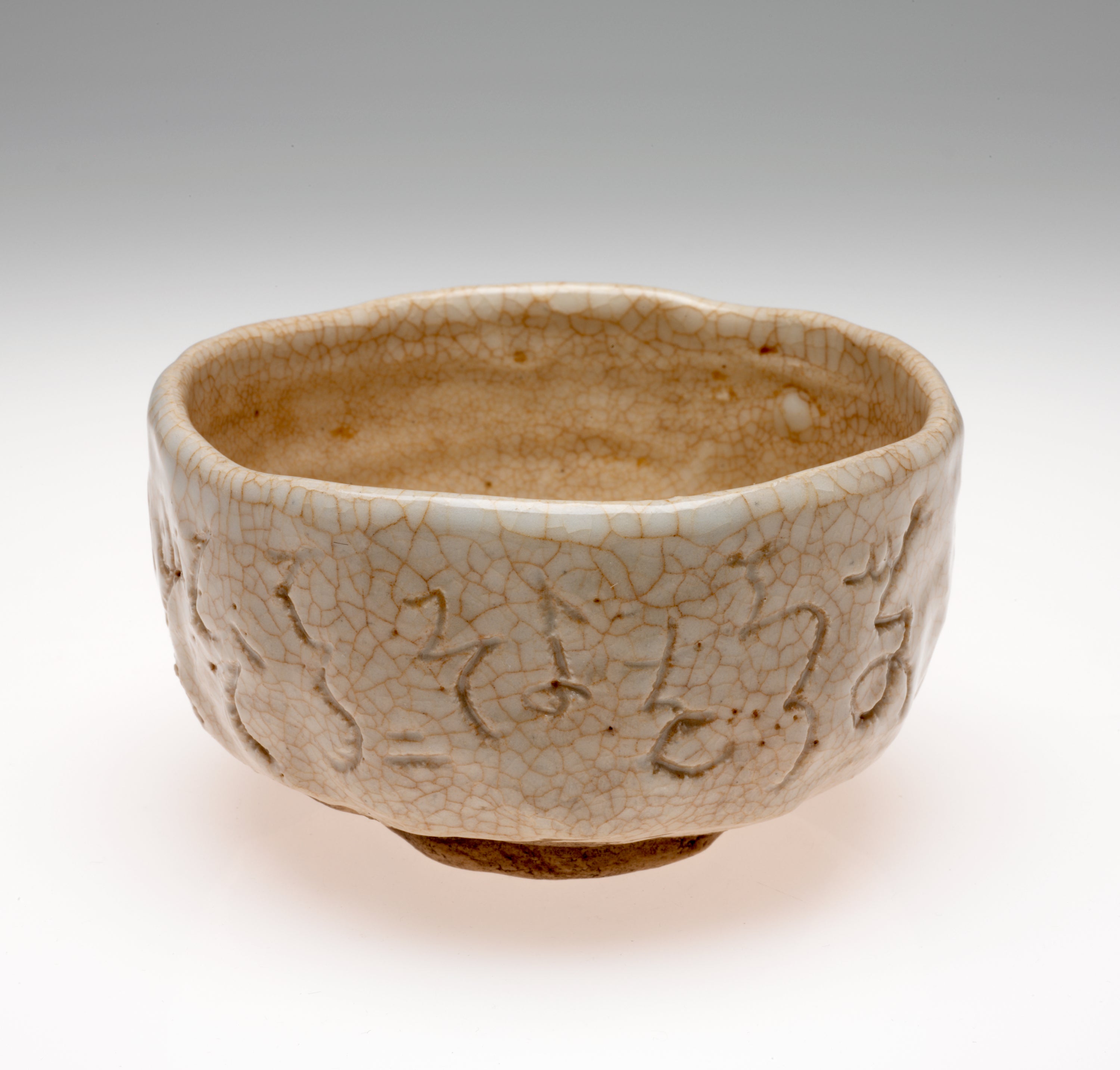 /A%20bowl%20with%20undulating%20sides%20and%20rim.%20Cream%20and%20brown%20colored%20with%20a%20crackled%20surface%20and%20abstract%20designs%20scratched%20into%20the%20surface.