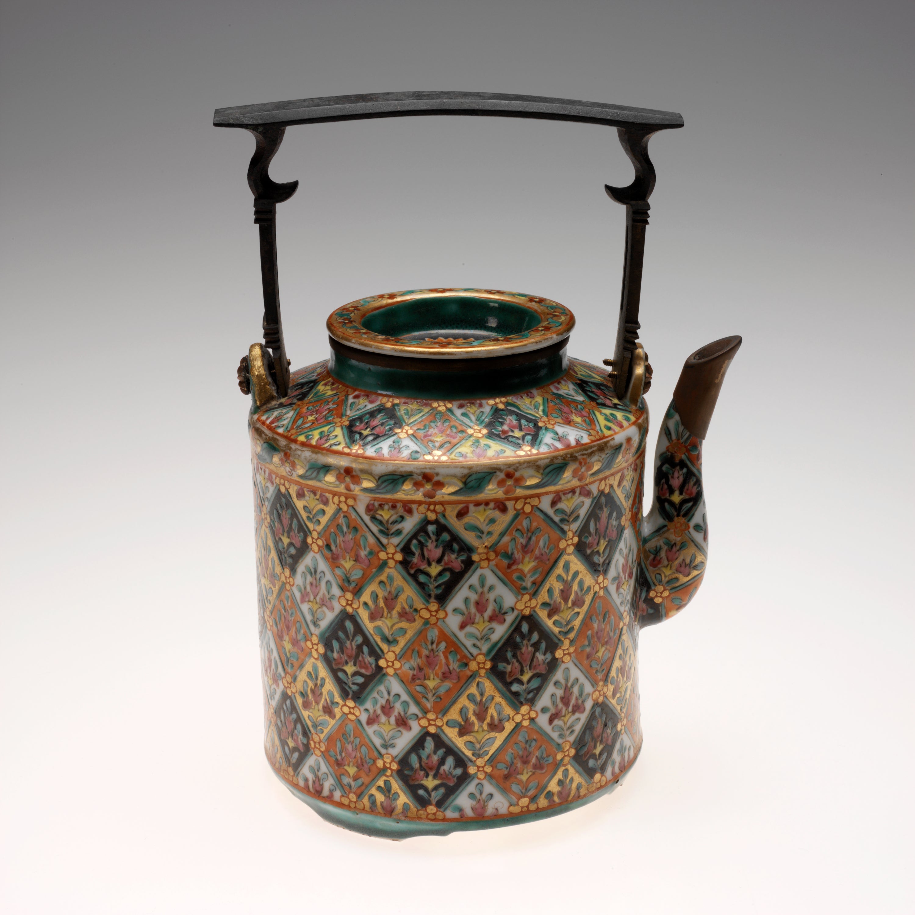 /A%20cylindrical%20teapot%20with%20an%20elaborate%20design%20of%20flowers%20inside%20diamond%20shapes%20of%20varying%20colors.%20A%20thin%2C%20square%20shaped%20handle%20with%20a%20flat%20top%20sits%20above%20the%20teapot.