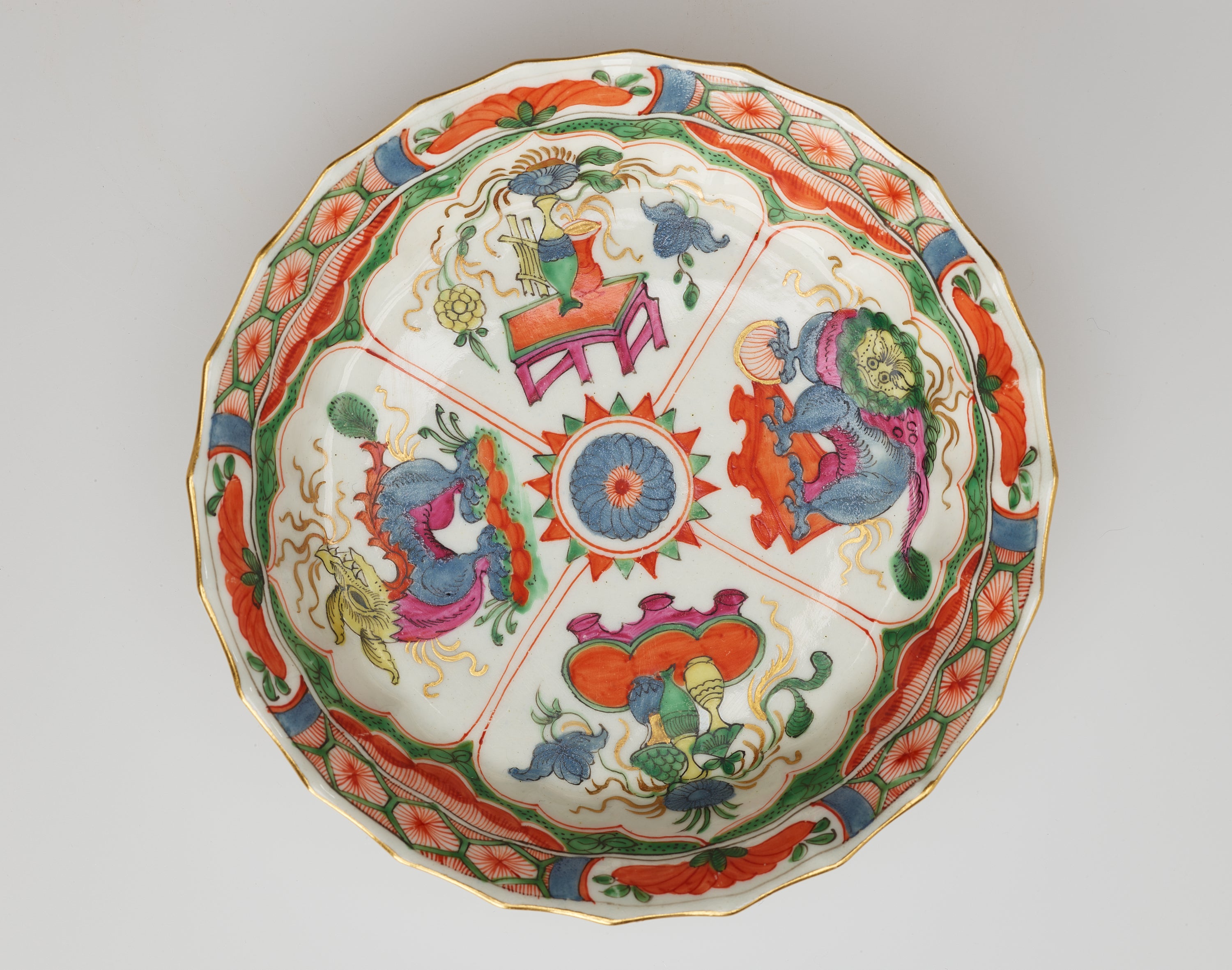 /A%20white%20saucer%20with%20green%2C%20red%2C%20blue%2C%20pink%2C%20yellow%2C%20and%20gilded%20decorations%3B%20separated%20into%20four%20main%20vignites%2C%20two%20animals%20and%20two%20tables%20and%20vessels%20containing%20floral%20elements.