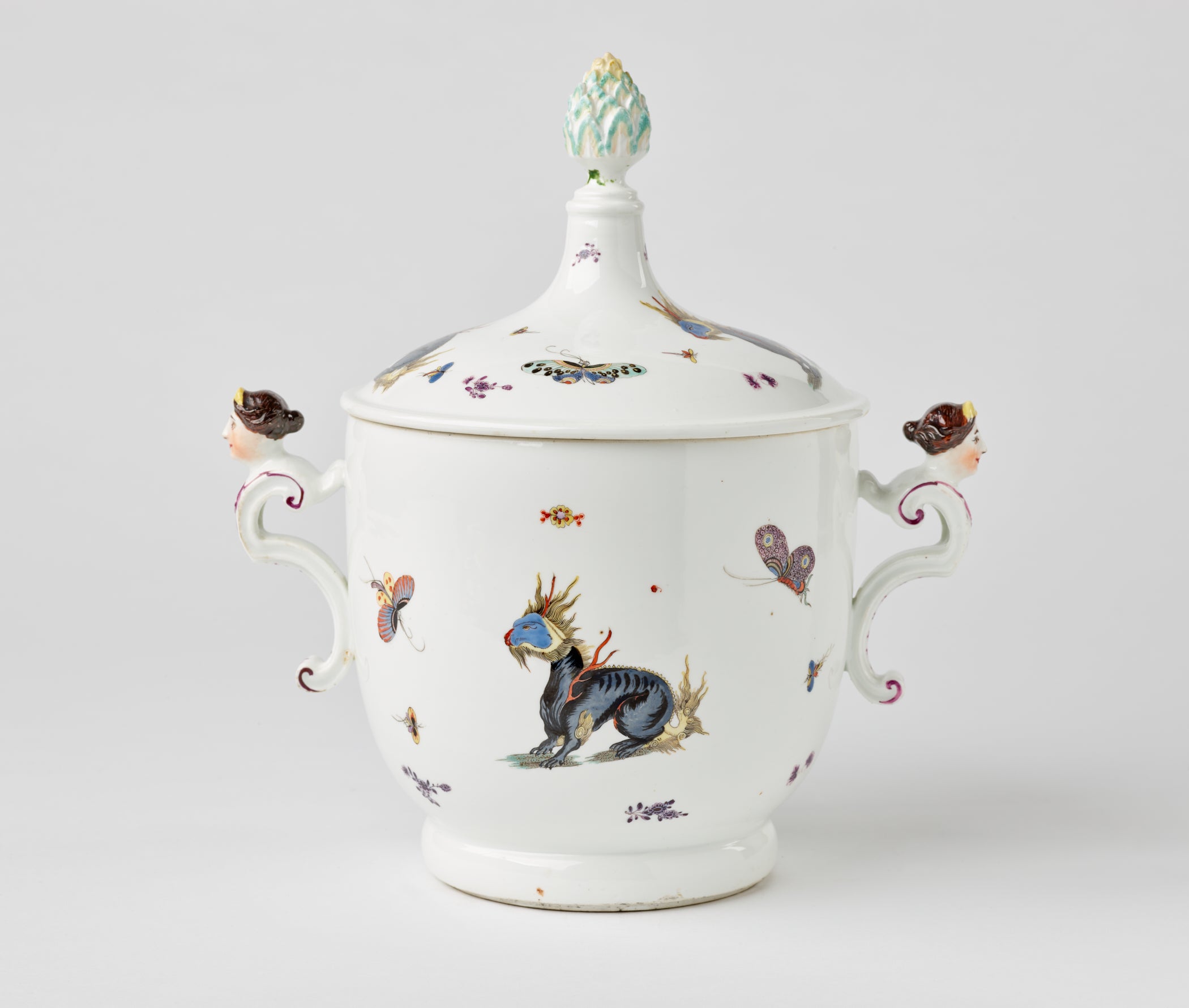 /A%20white%20porcelain%20icecream%20pail%20with%20dragons%20and%20bugs%20decorations%2C%20there%20are%20two%20sculptural%20handles%20that%20are%20figure%E2%80%99s%20heads%2C%20the%20lid%20has%20a%20sculptural%20finial.