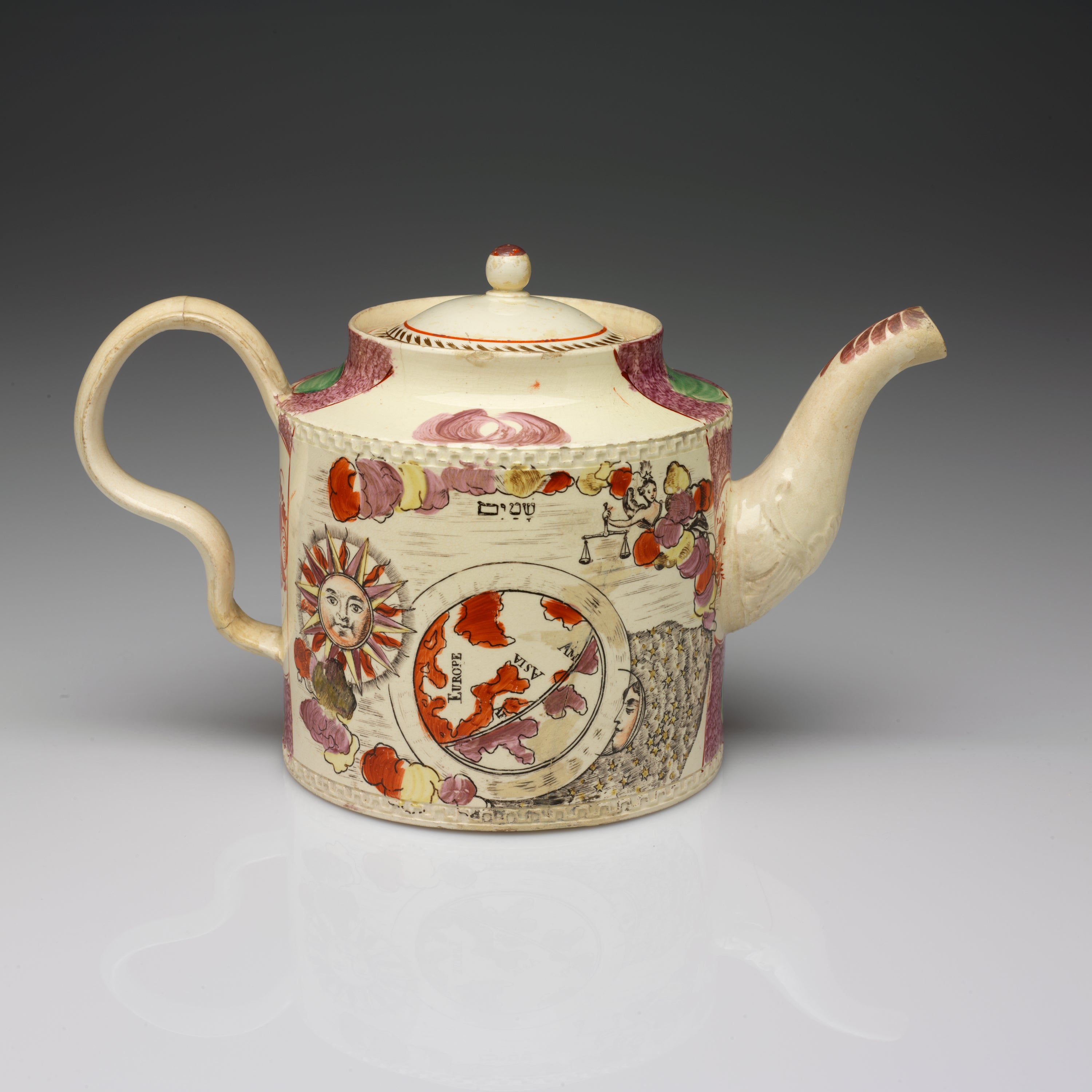 /A%20cylindrical%20teapot%20with%20an%20inward%20curve%20towards%20the%20lid%2C%20a%20wavy%20handle%2C%20and%20a%20spout.%20The%20transfer%20printed%20decorations%20are%20a%20sun%2C%20a%20map%2C%20and%20a%20figure%20holding%20scales.