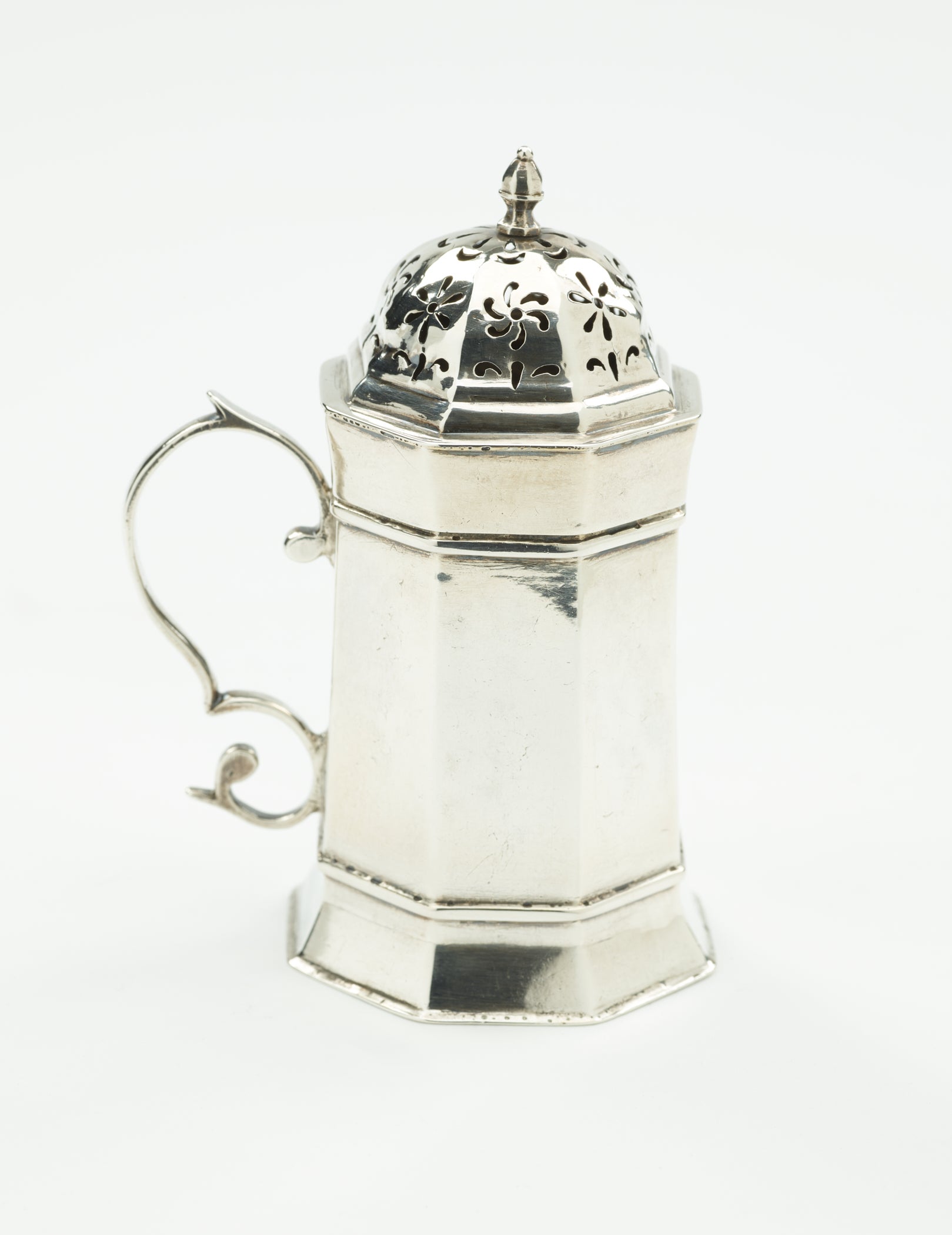 /A%20silver%20caster%20that%20has%20an%20octagonal%20body%2C%20handle%2C%20and%20lid%20that%20has%20floral%20perforations.