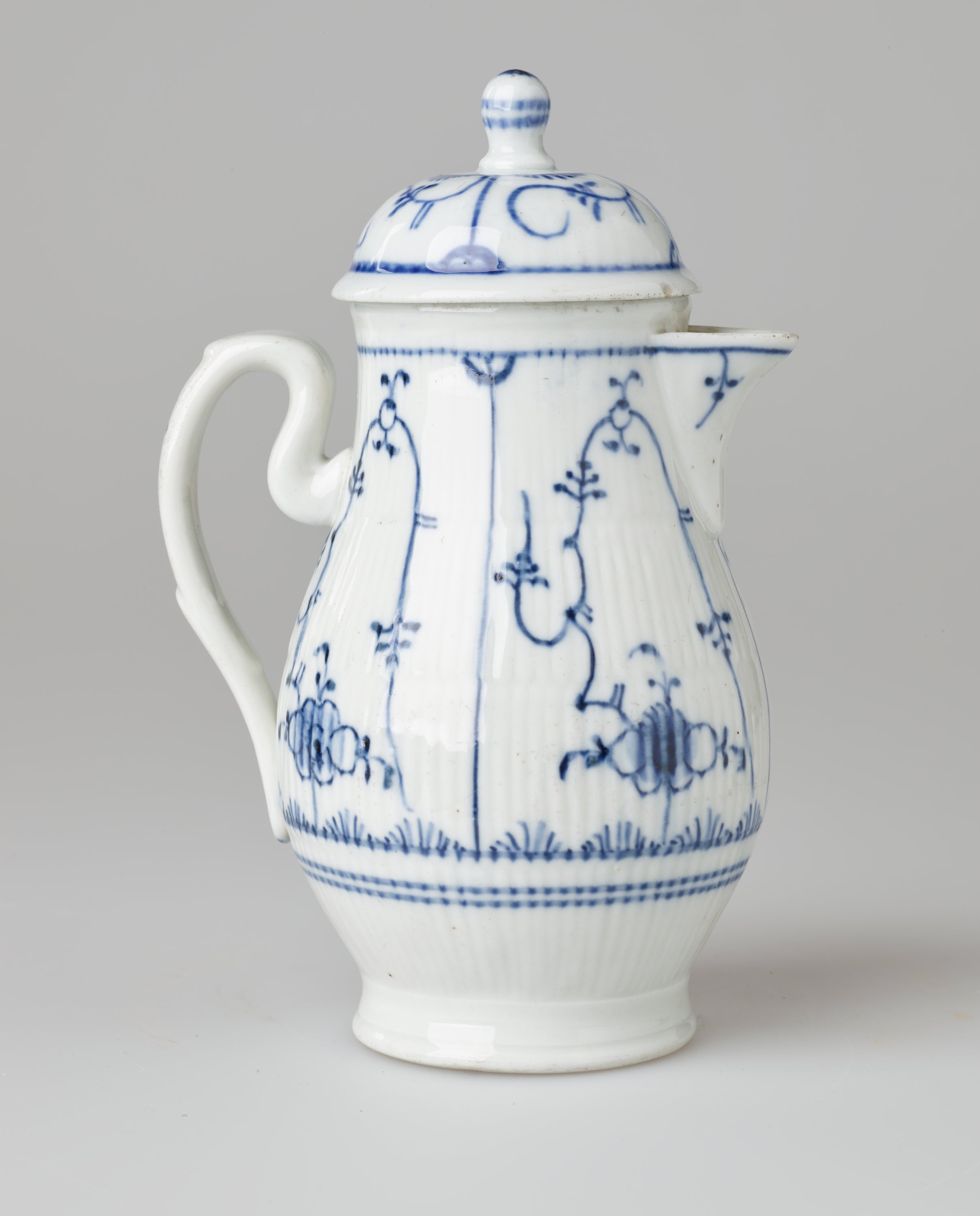 /A%20white%20ceramic%20chocolate%20pot%20with%20delicate%20blue%20decorations%20with%20ribbed%20body%2C%20spout%2C%20handle%2C%20and%20foot.