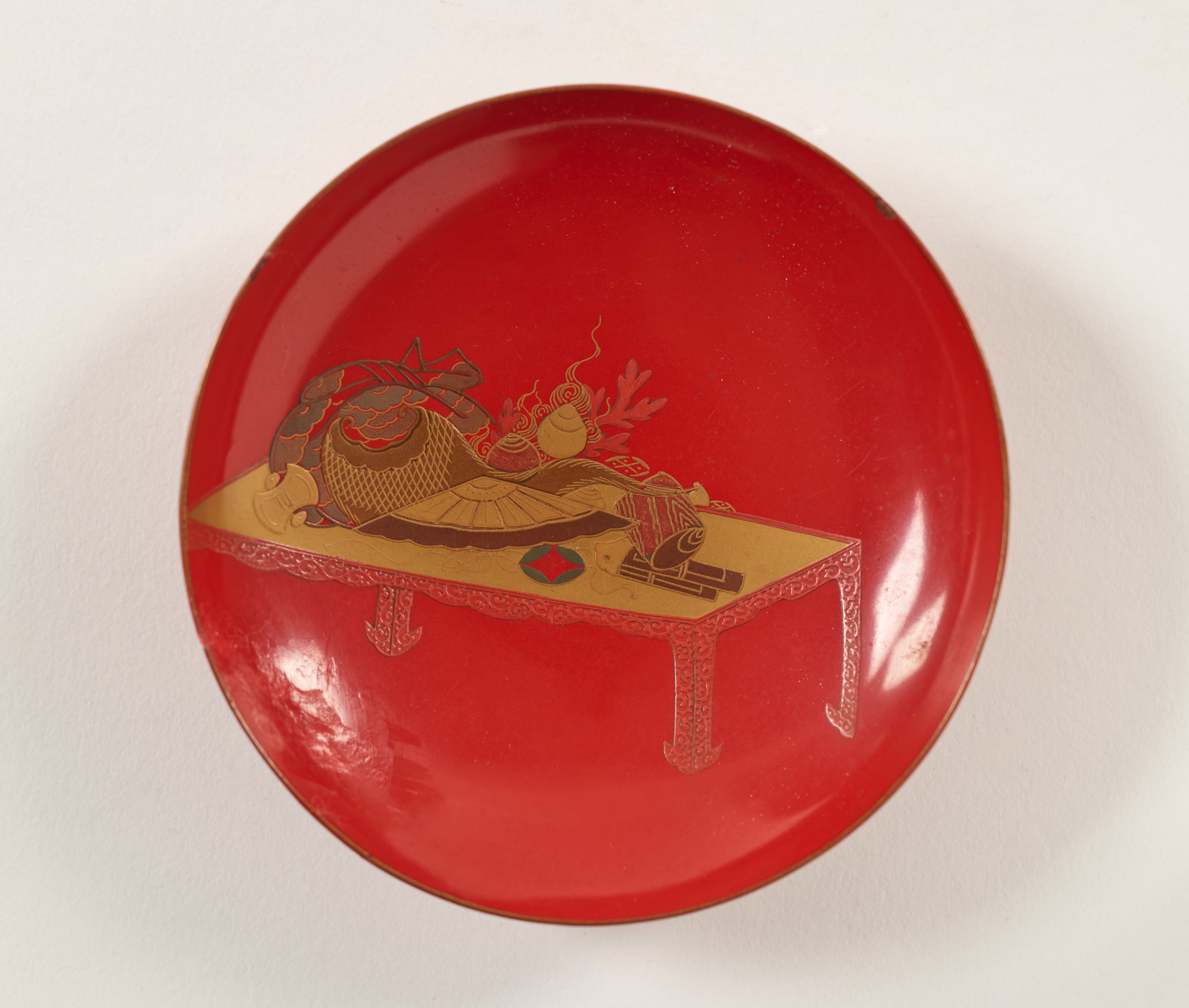 /A%20lacquered%20wood%20wine%20cup%20that%20is%20bright%20red%20and%20has%20gold%20decorations.%20