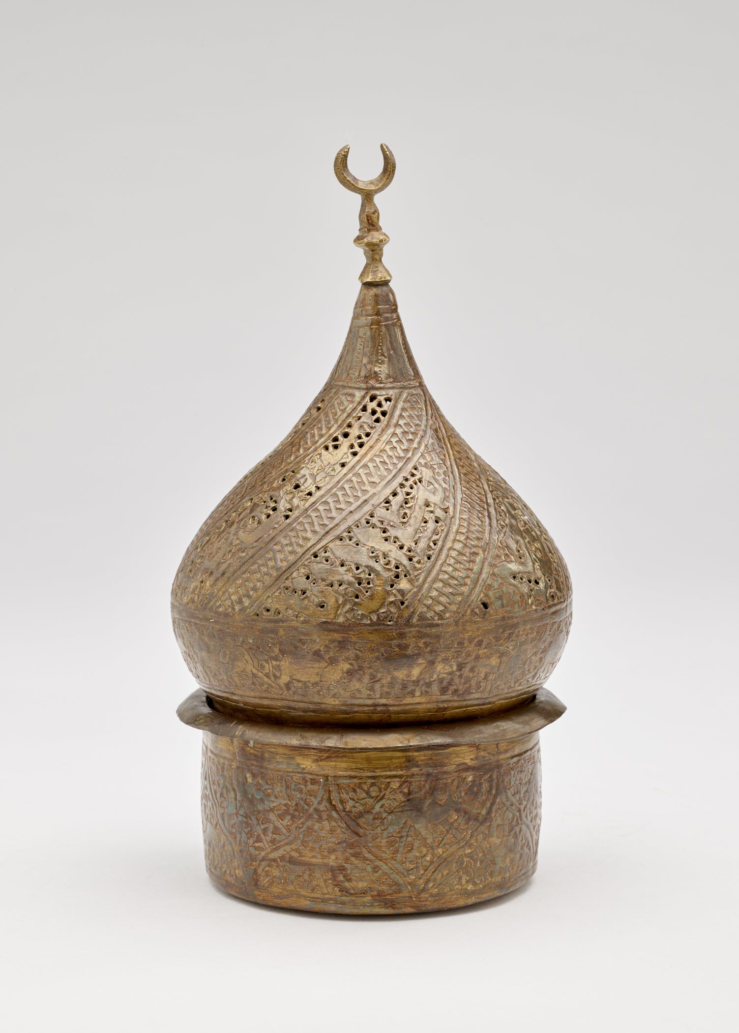 /Bronze-colored%20sculptural%20object%20with%20incised%20design.%20Top%20half%20is%20teardrop%20shaped%20with%20a%20crescent%20moon%20shape%20on%20top.%20Cylindrical%20vessel%20on%20bottom.%20