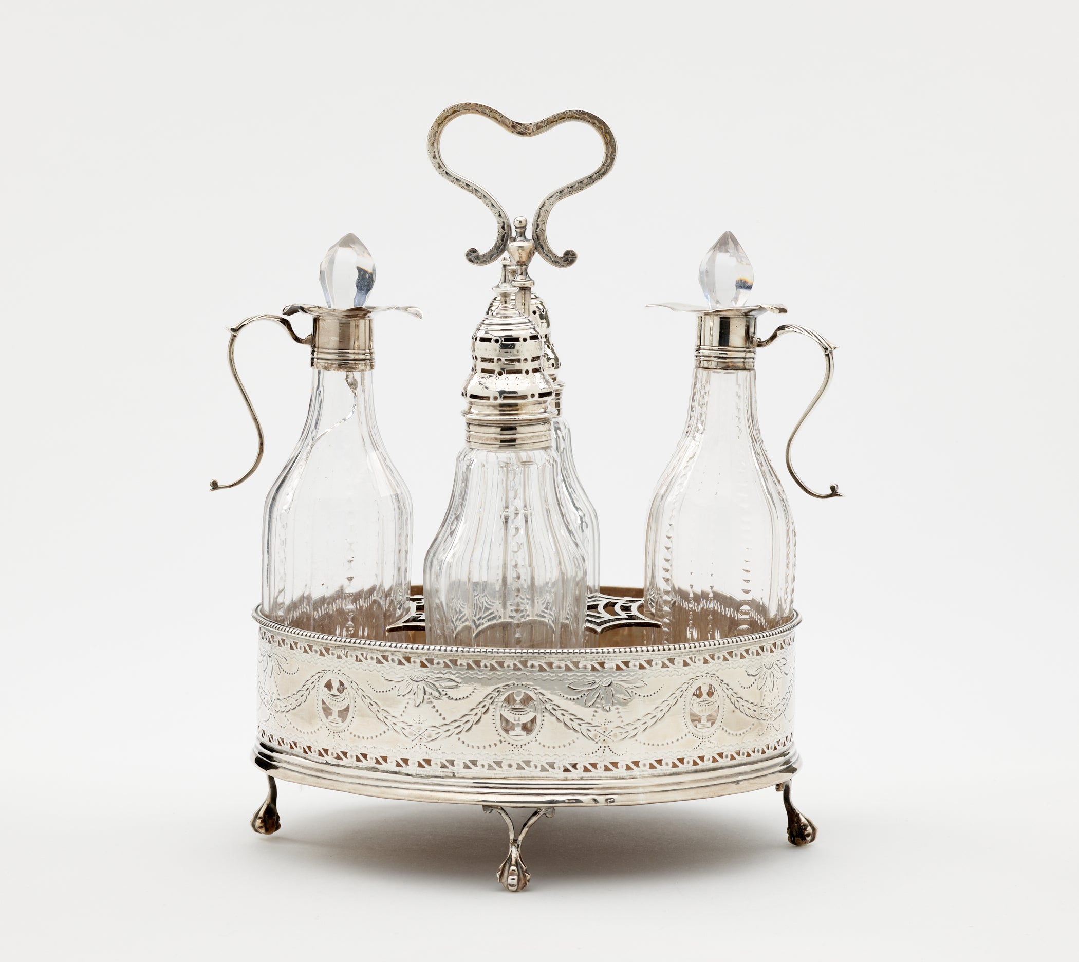 /A%20silver%2C%20mahogany%2C%20and%20glass%20caster%20set.%20There%20are%20various%20vessels%20inside%20the%20footed%20tray.%20The%20silver%20and%20glass%20has%20etched%20decorations.