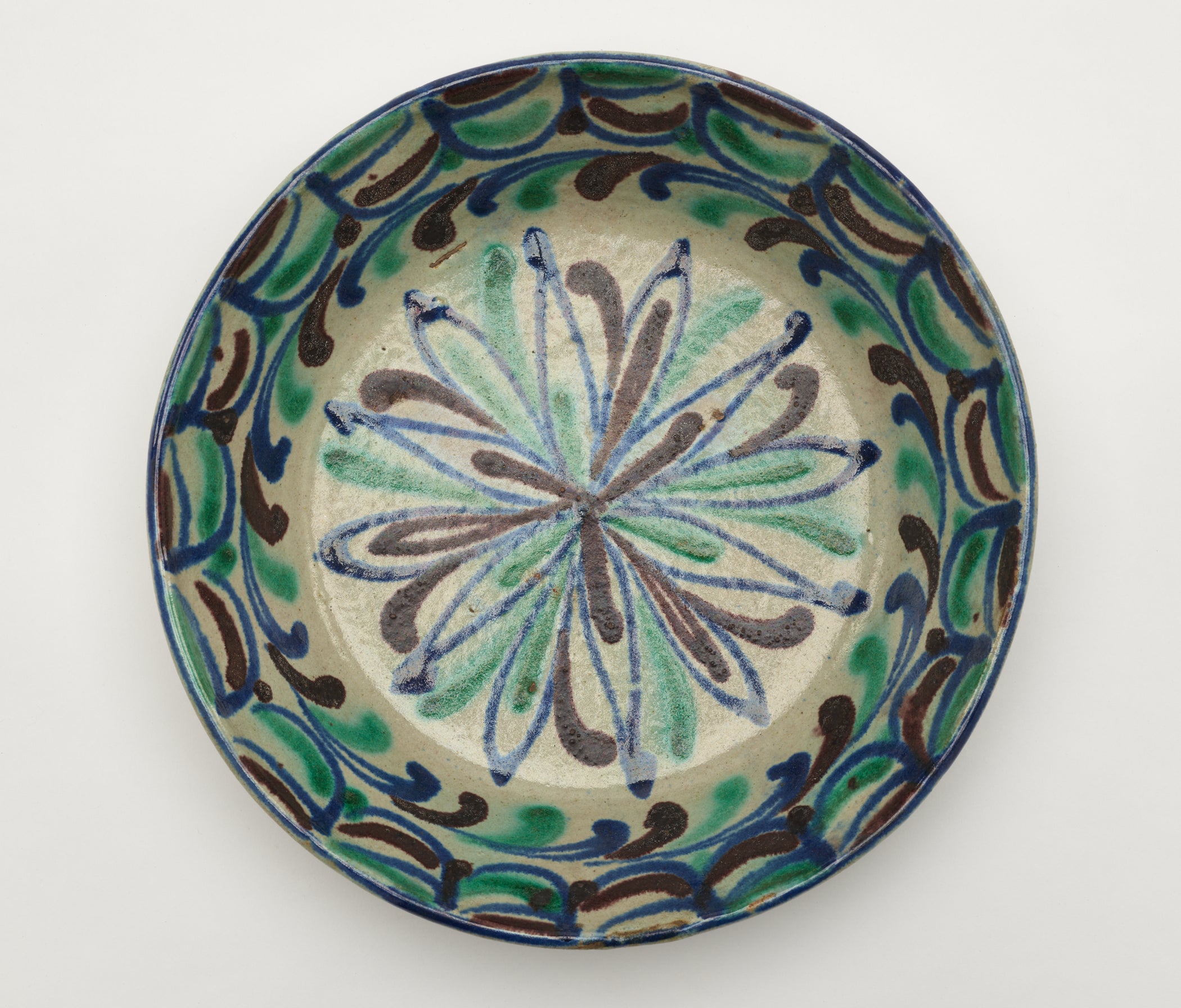 /A%20gray-white%20circular%20cooking%20placate%20with%20blue%2C%20green%2C%20and%20gray%20symmetrical%20linear%20decorations.