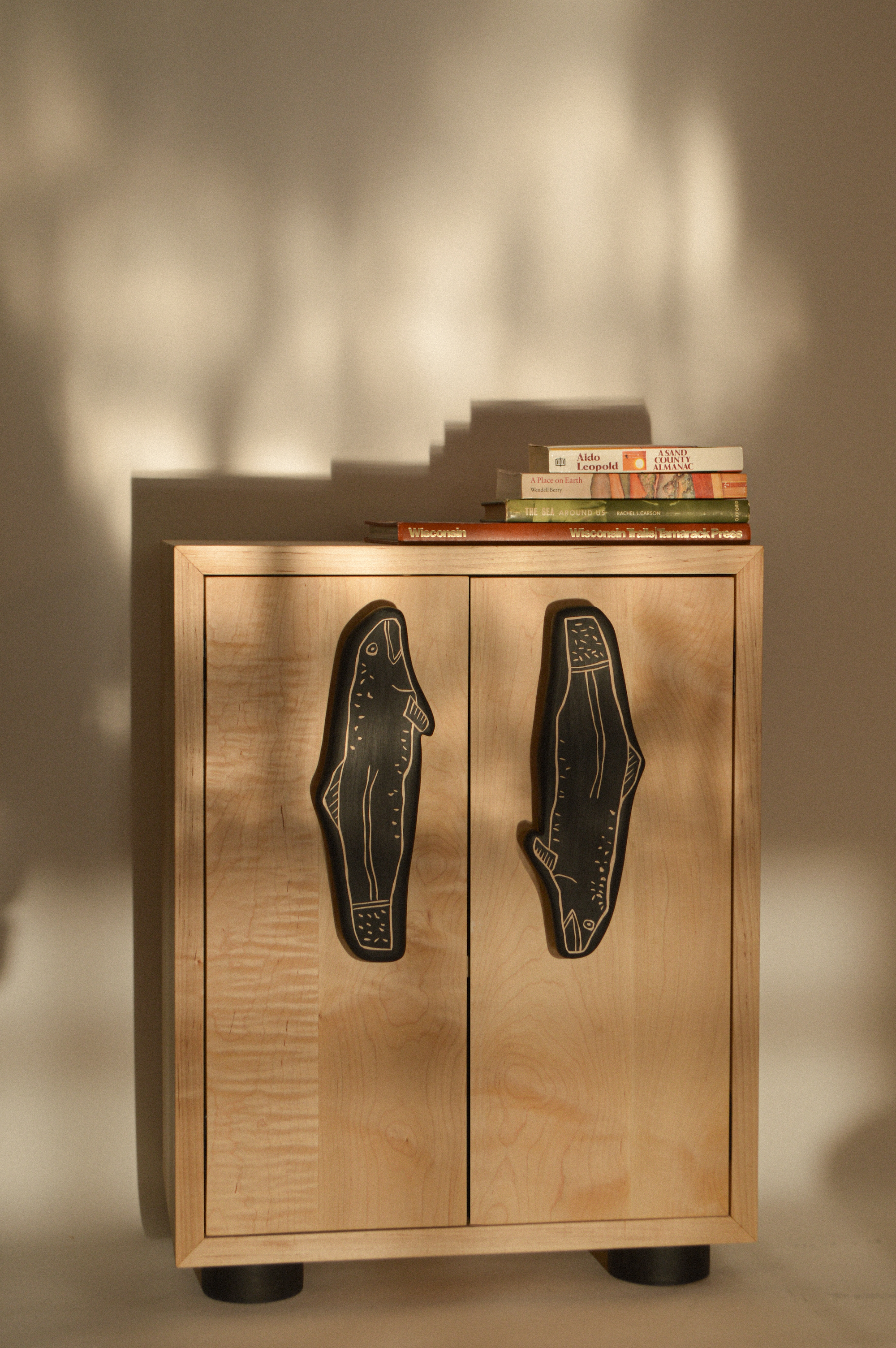 a small solid maple cabinet with oversized handles shaped like fish