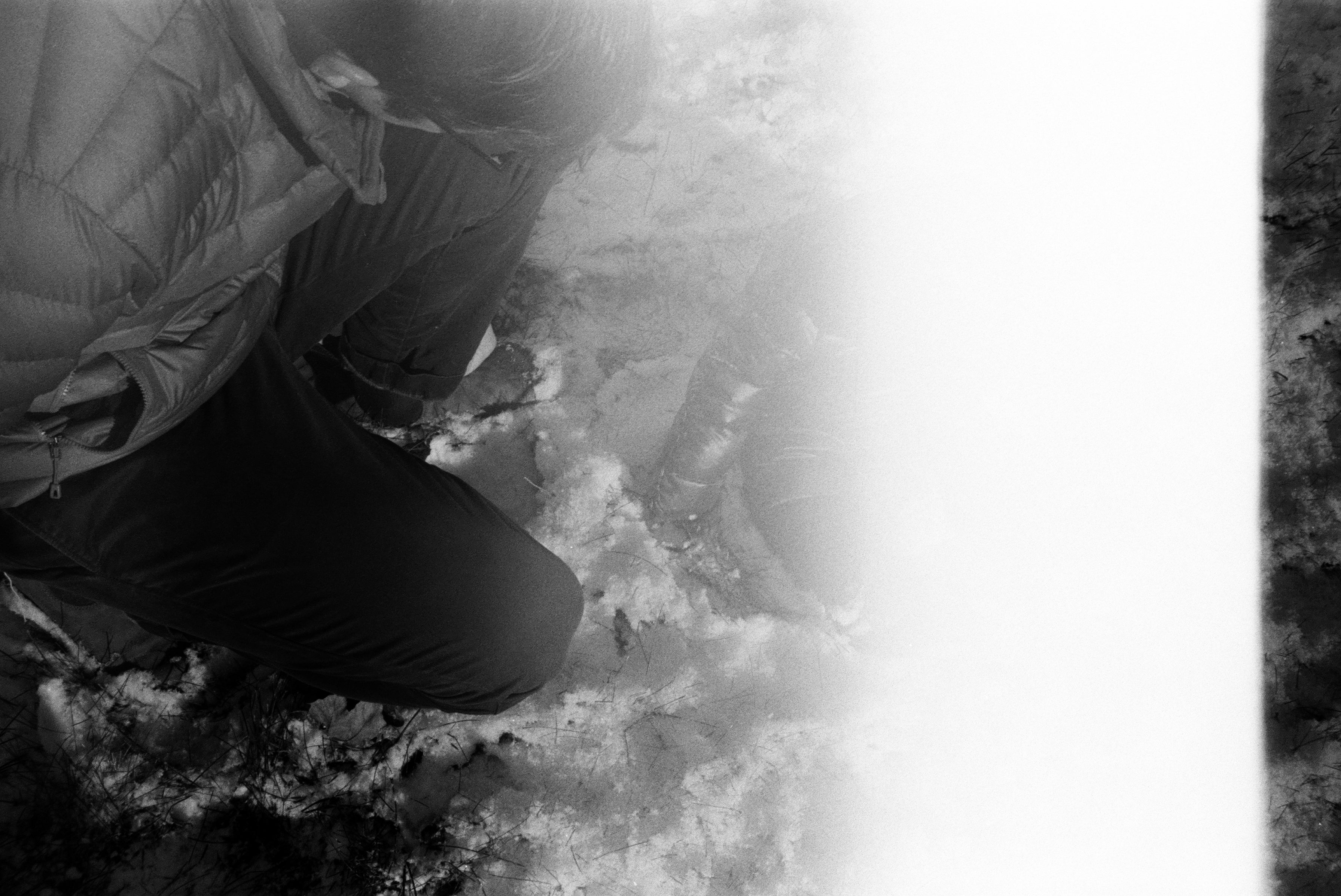 an adult man (my partner) and a baby (my son) in the snow, a light leak enveloping much of the photo, moving from right to left