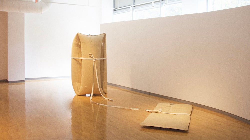 Three large inflated brown tone bag held by a fabric belt on the left side, One deflated bag on the right side.
