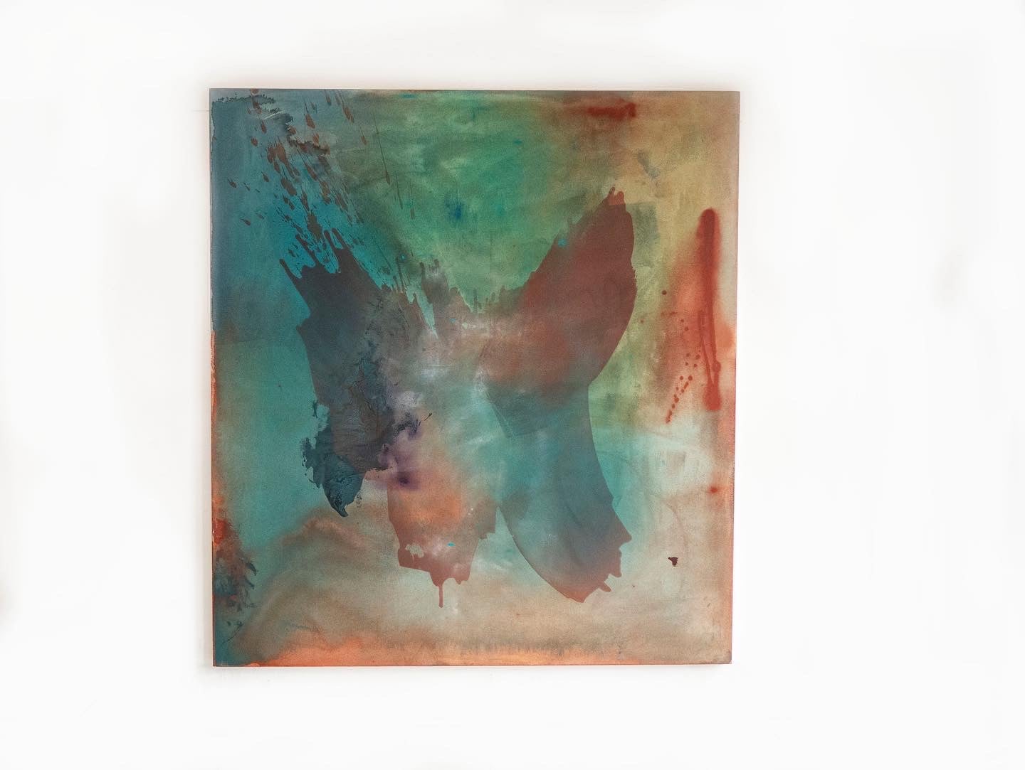 An abstract painting on stretched canvas in washes of color- yellowfins, blue, green- with a muted form in the middle resembling butterfly wings.
