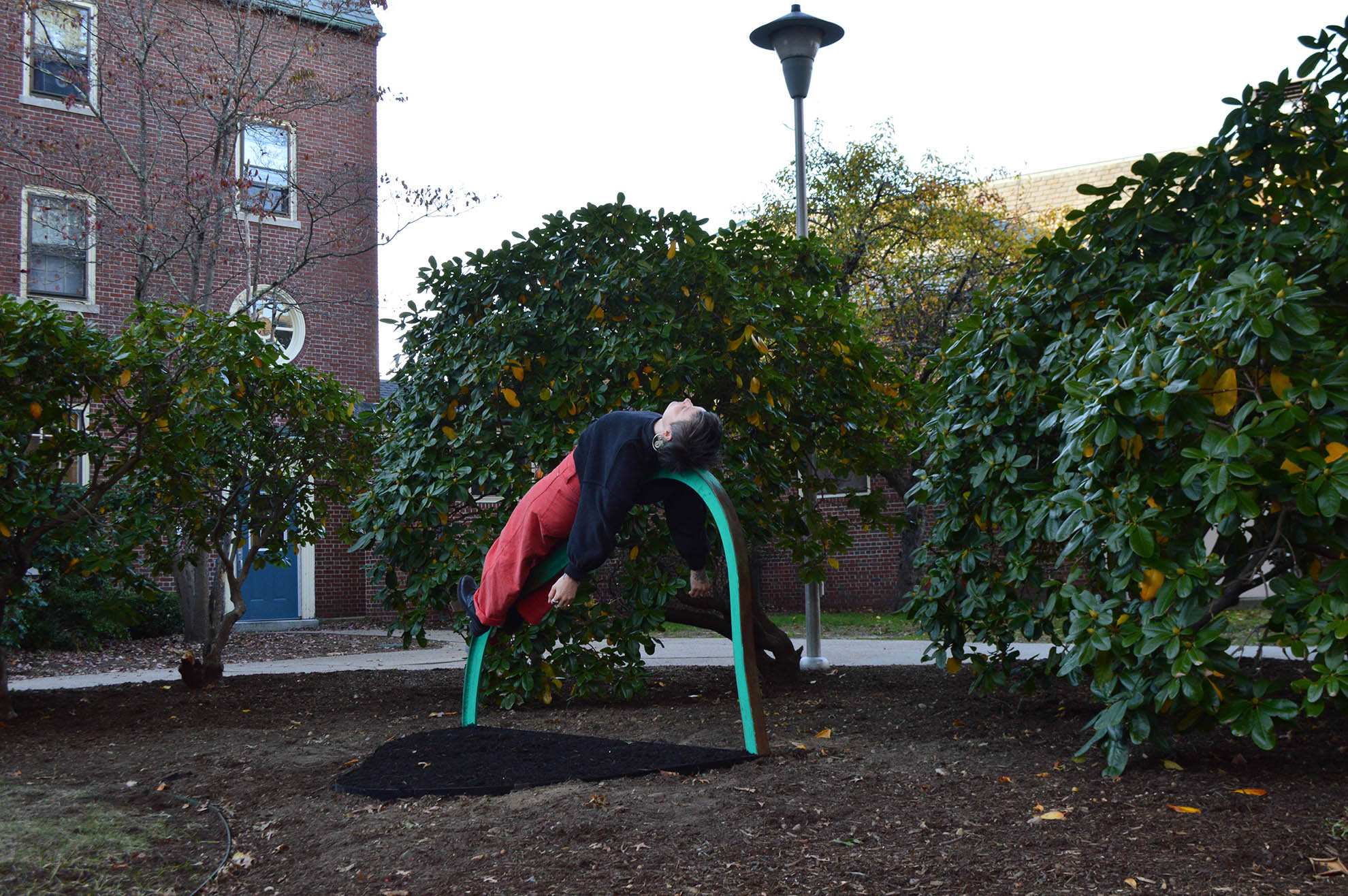 The artist lies across a zinc-chromate green steel armature, nestled among trees.