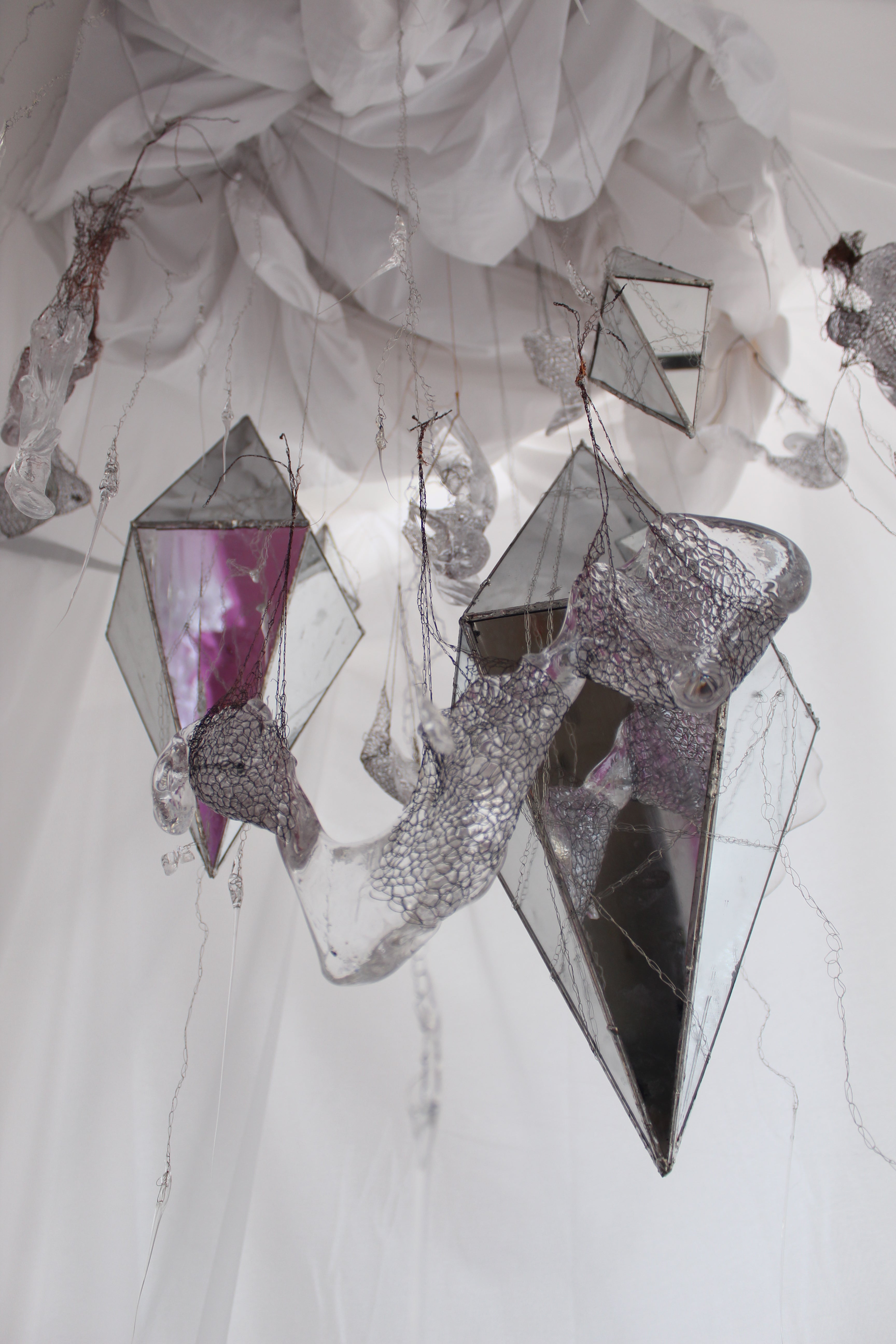 Mirrors in the shape of diamonds hang from the ceiling along with glass pieces.  All are suspended by metal crochet weavings.