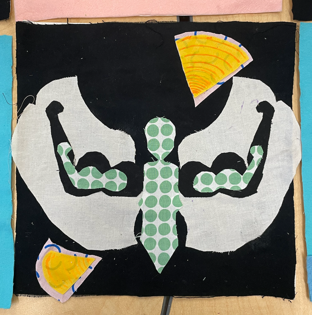 In progress student artwork, fabric quilt block showing a person with big muscles, angel wings, and sound waves radiating off them