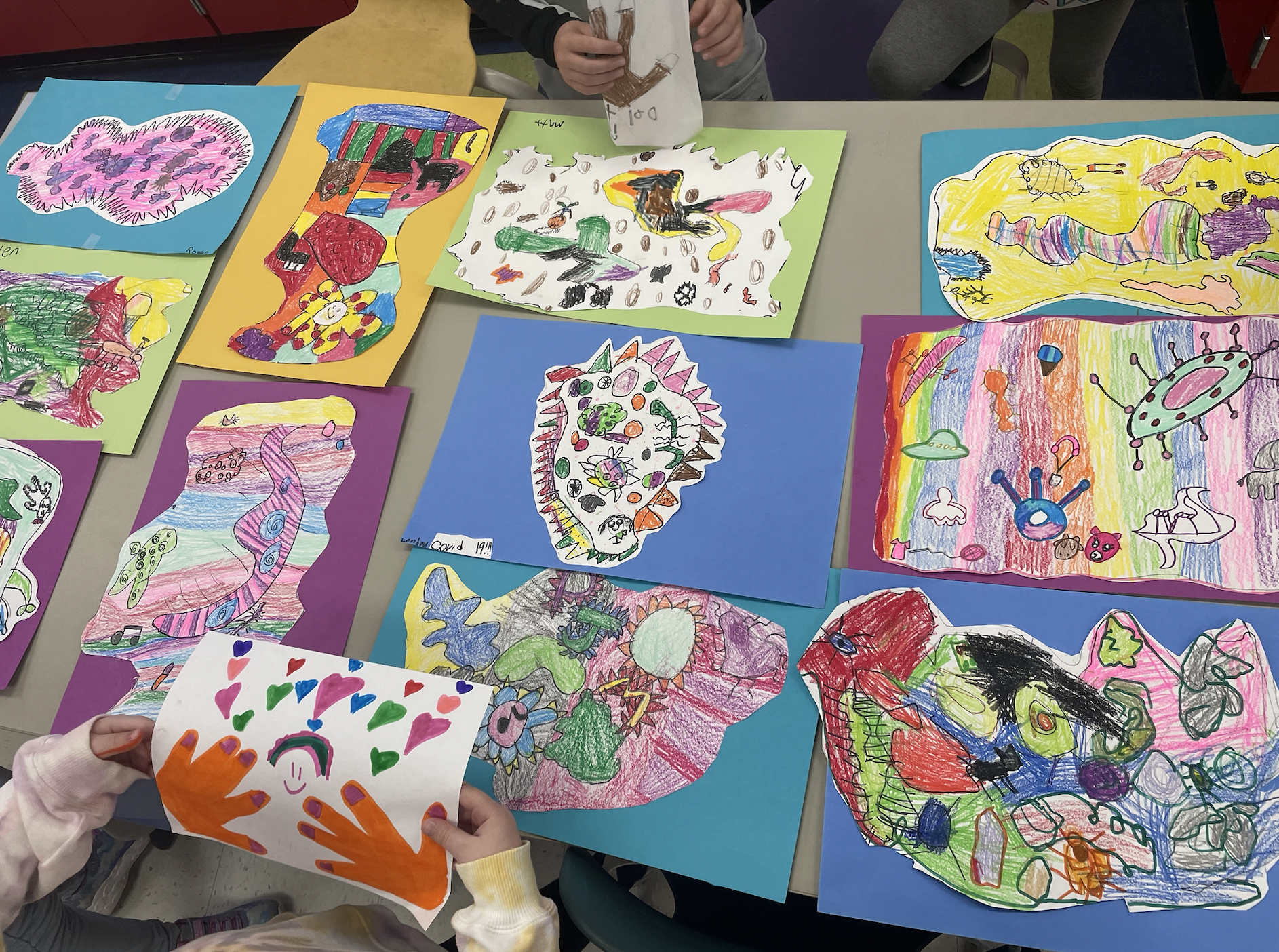 A group of 1st graders art works laid out on a table.